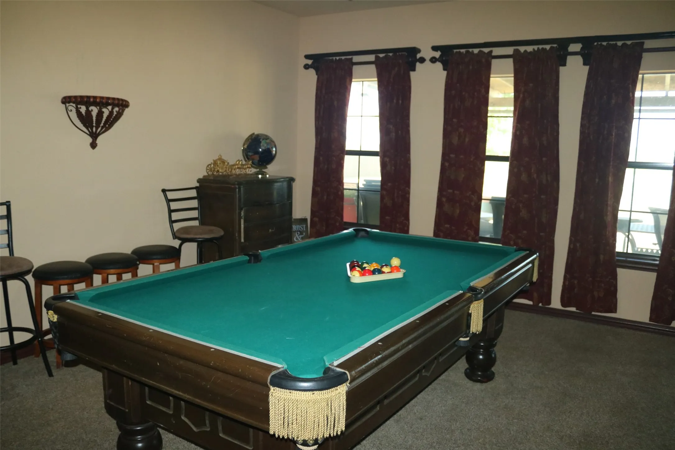 Recreation room featuring a billiard table with green felt, multiple windows, and a built-in wall sconce
