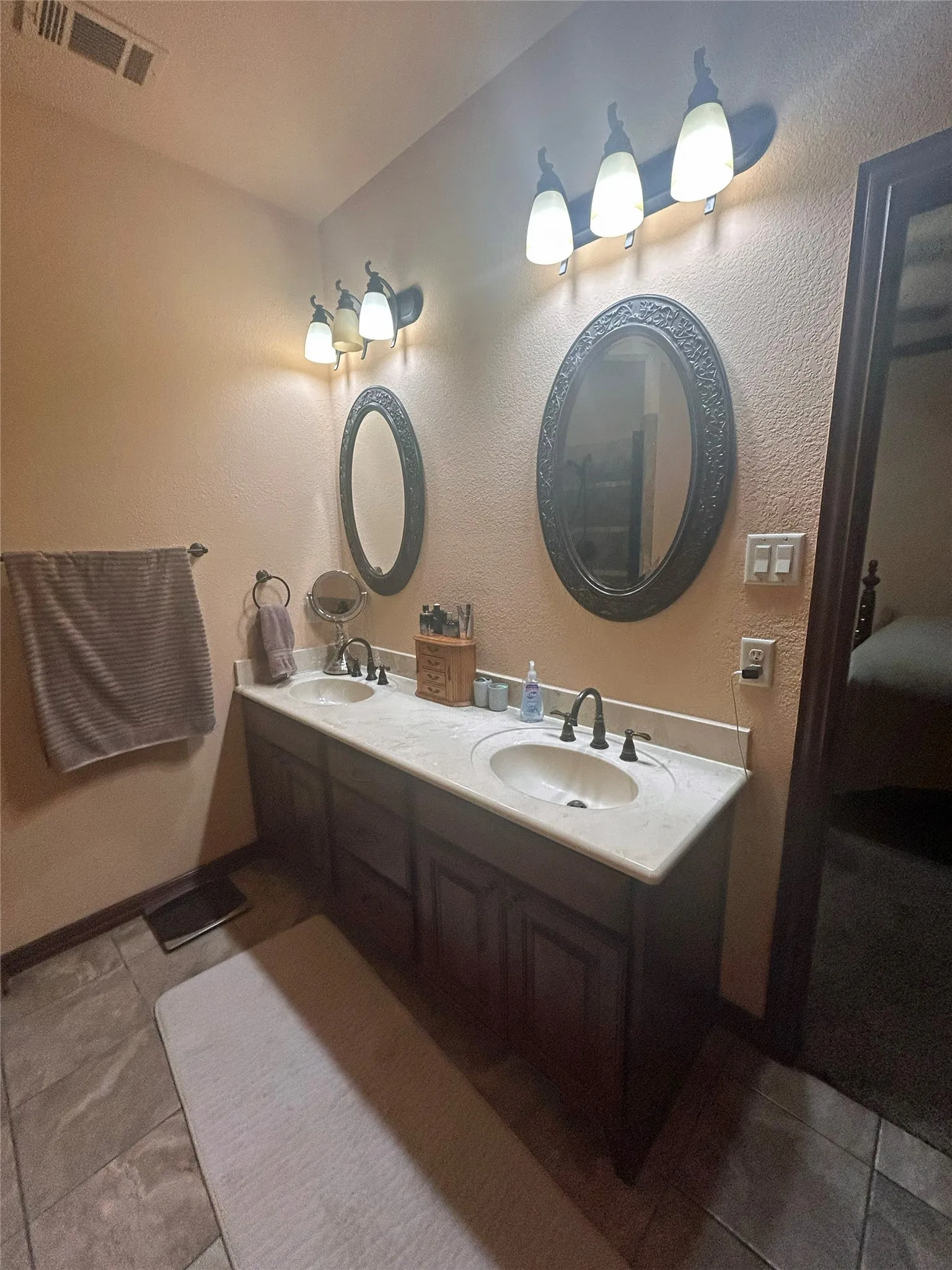 Dual vanity with integrated sinks, stone-look countertop, and dark wood-finish cabinetry