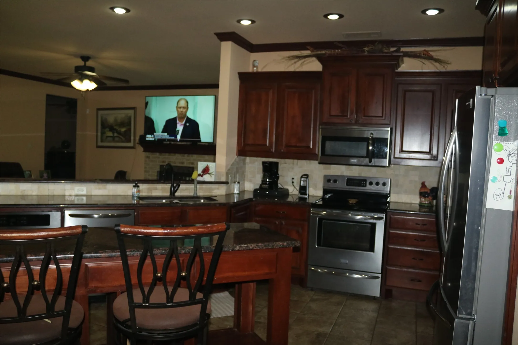Kitchen featuring dark wood cabinetry, stainless steel appliances, recessed lighting, and a breakfast bar with stone countertops