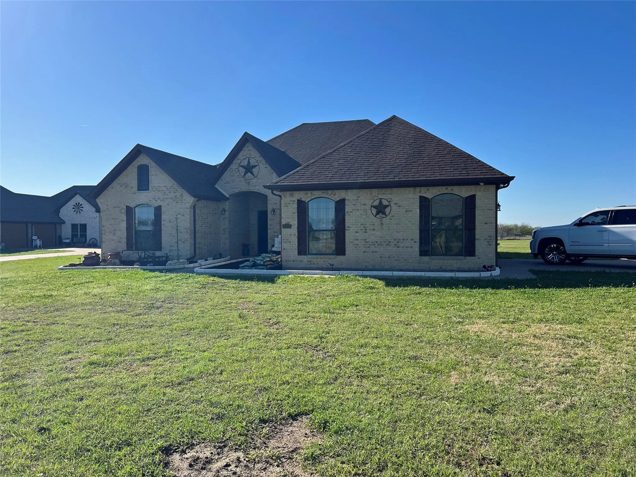 Brick exterior with dark roof shingles, arched windows, and decorative shutters