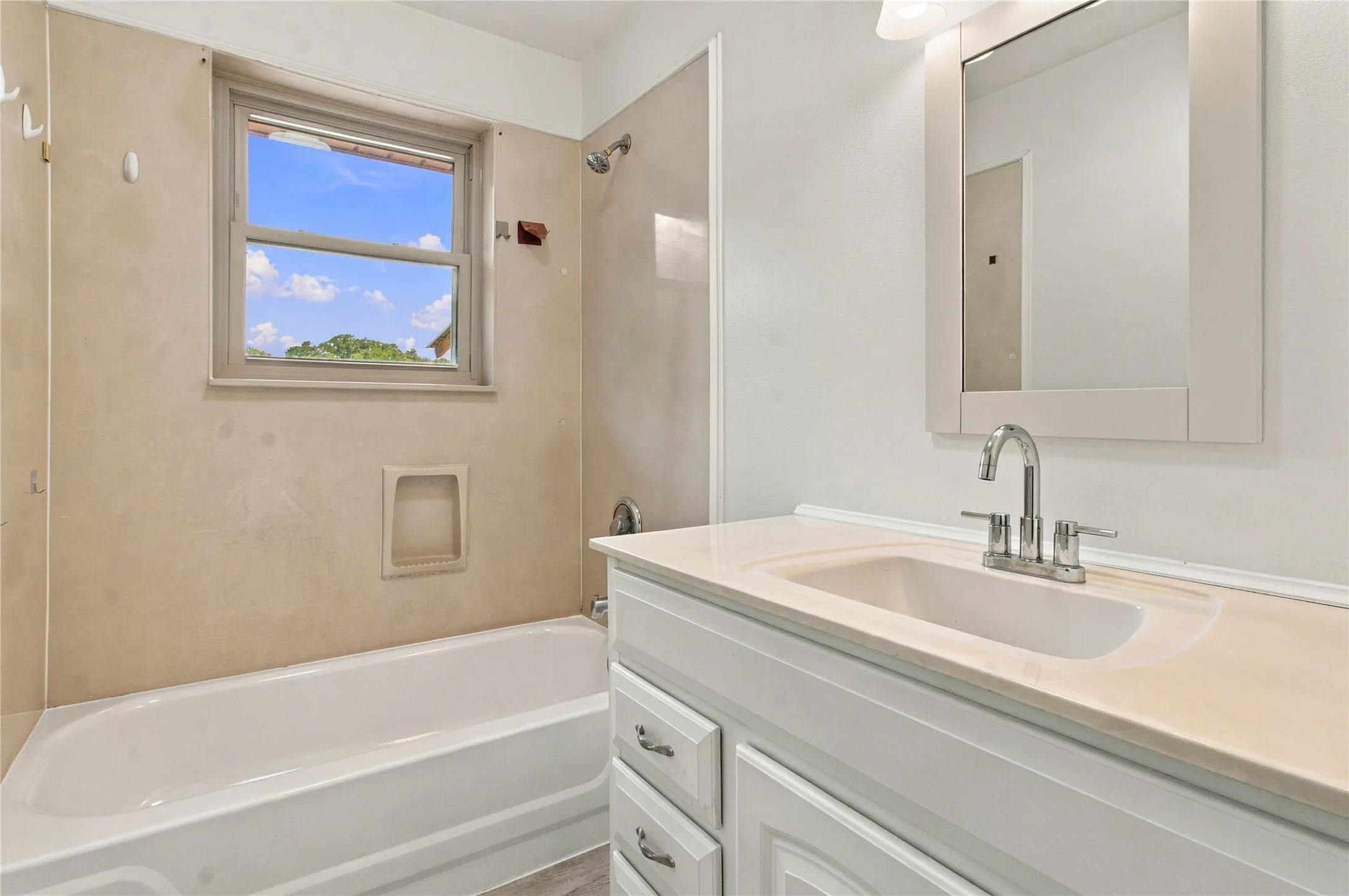 White vanity with a light-toned countertop and integrated sink