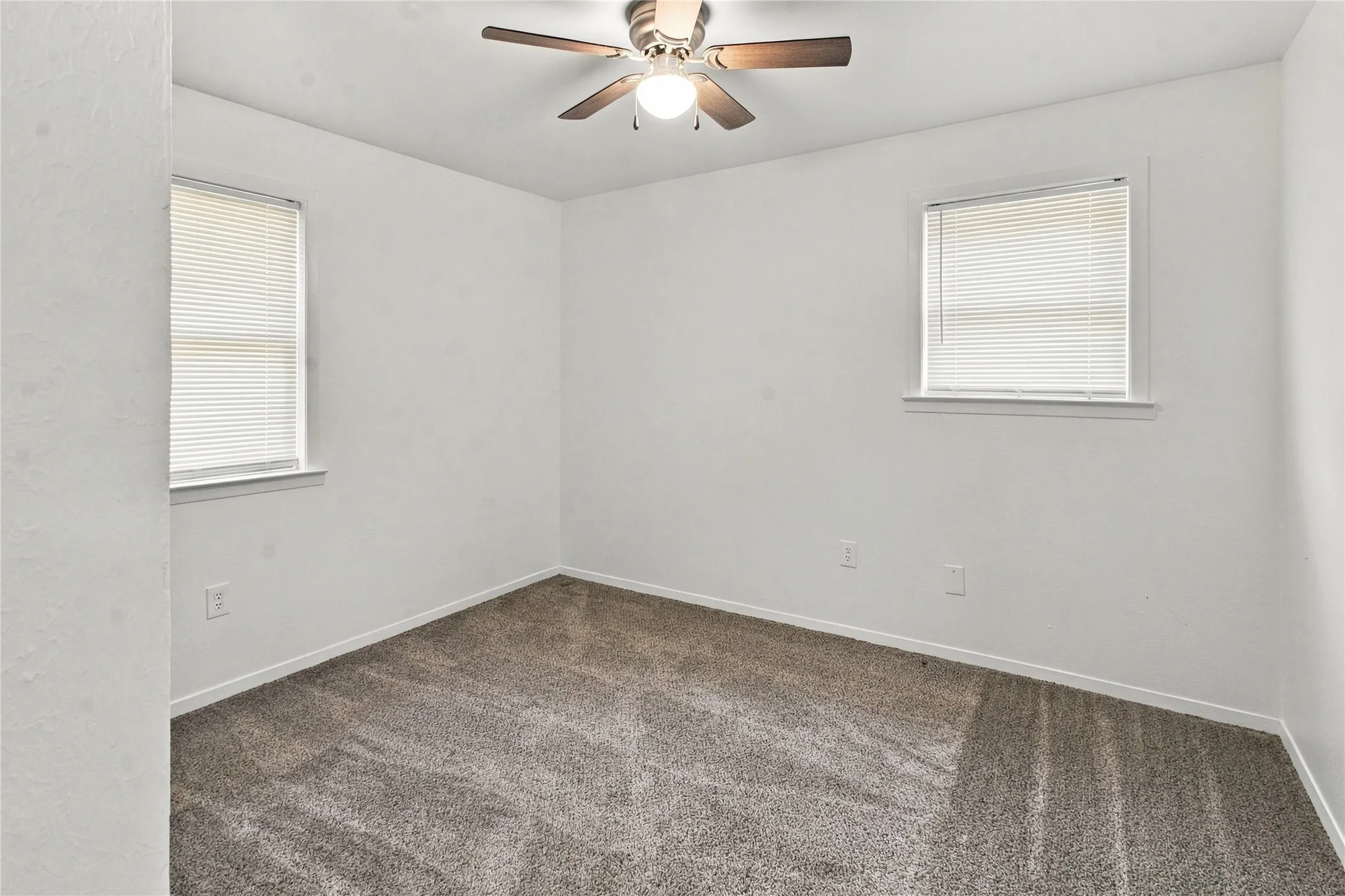 Plush carpeting, neutral wall finishes, and a ceiling fan with integrated lighting