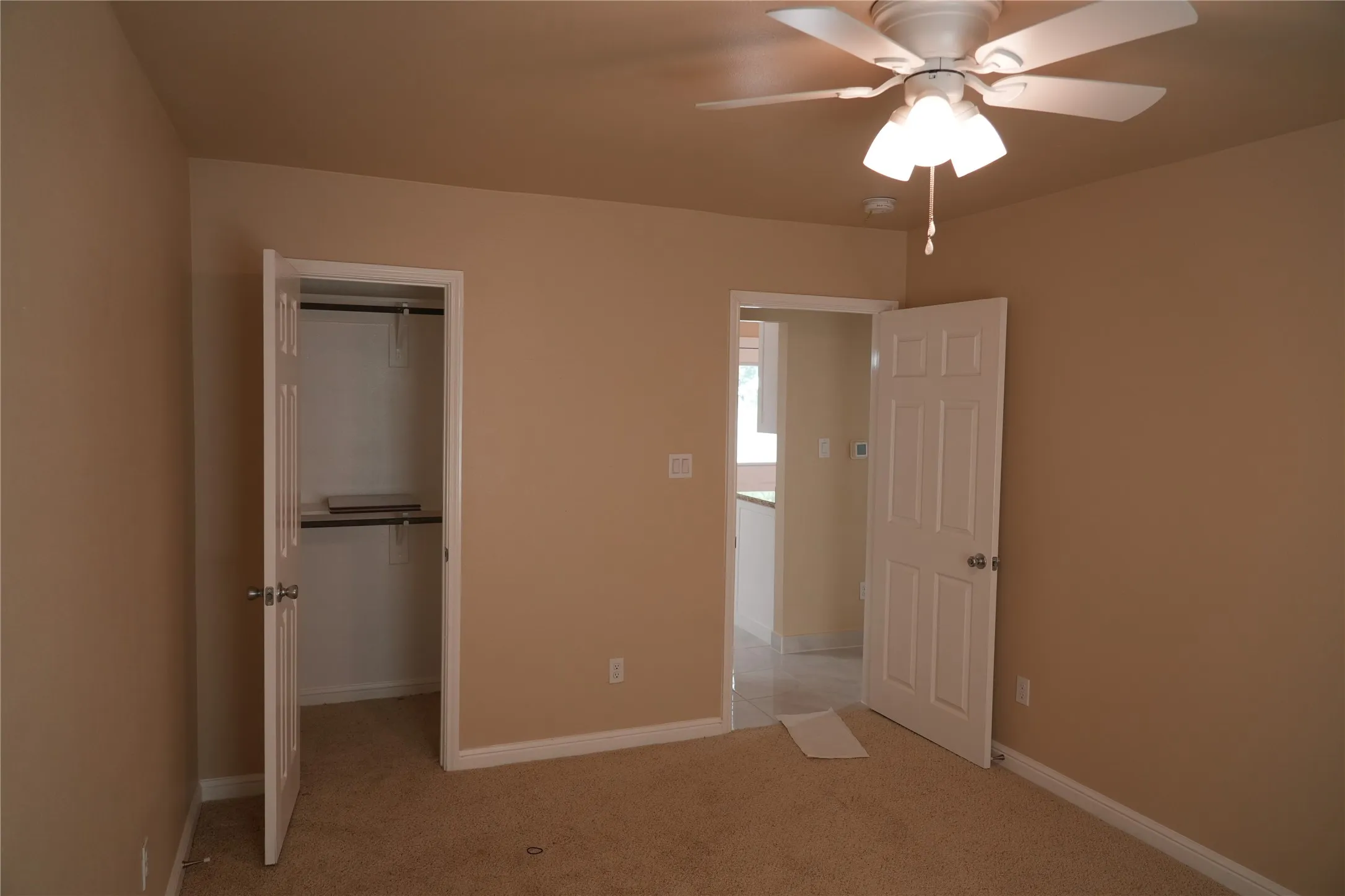 Neutral wall color, ceiling fan with integrated lighting, paneled interior doors, and carpet flooring