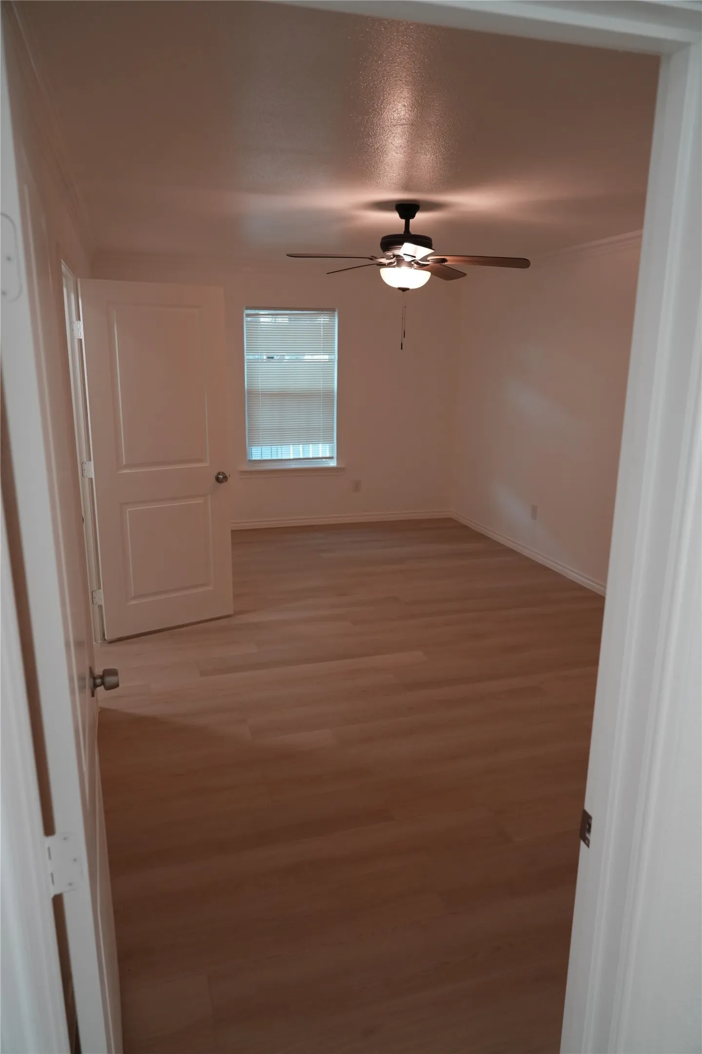 Wood-finish plank flooring, ceiling fan with integrated lighting, and a window with blinds