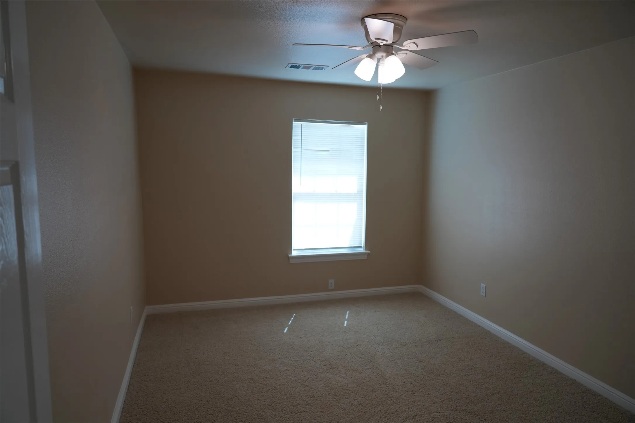 Neutral tone wall paint, carpeted flooring, window with blinds, and ceiling fan with integrated lighting