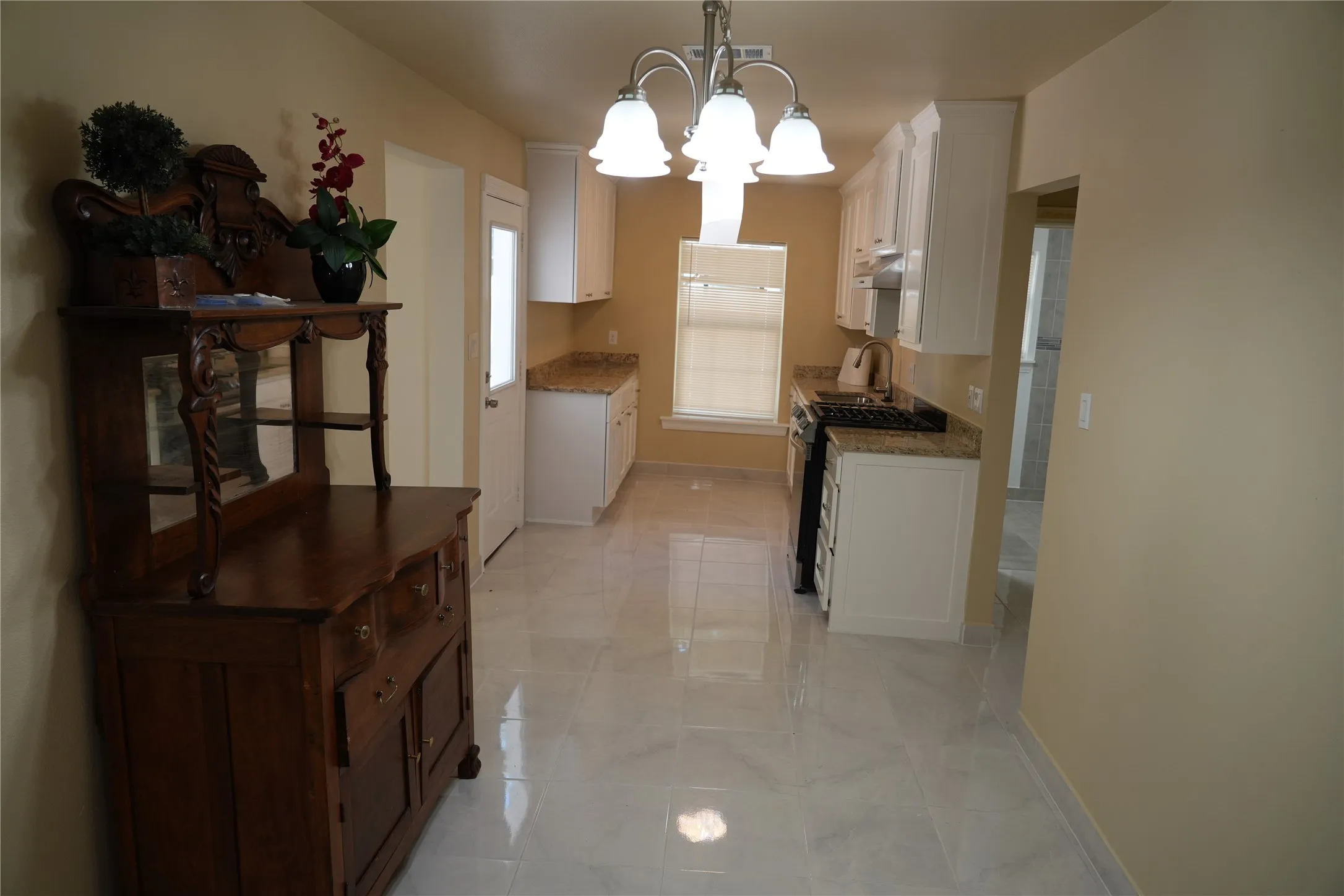 White shaker cabinetry with granite countertops, stainless steel appliances, and tile flooring