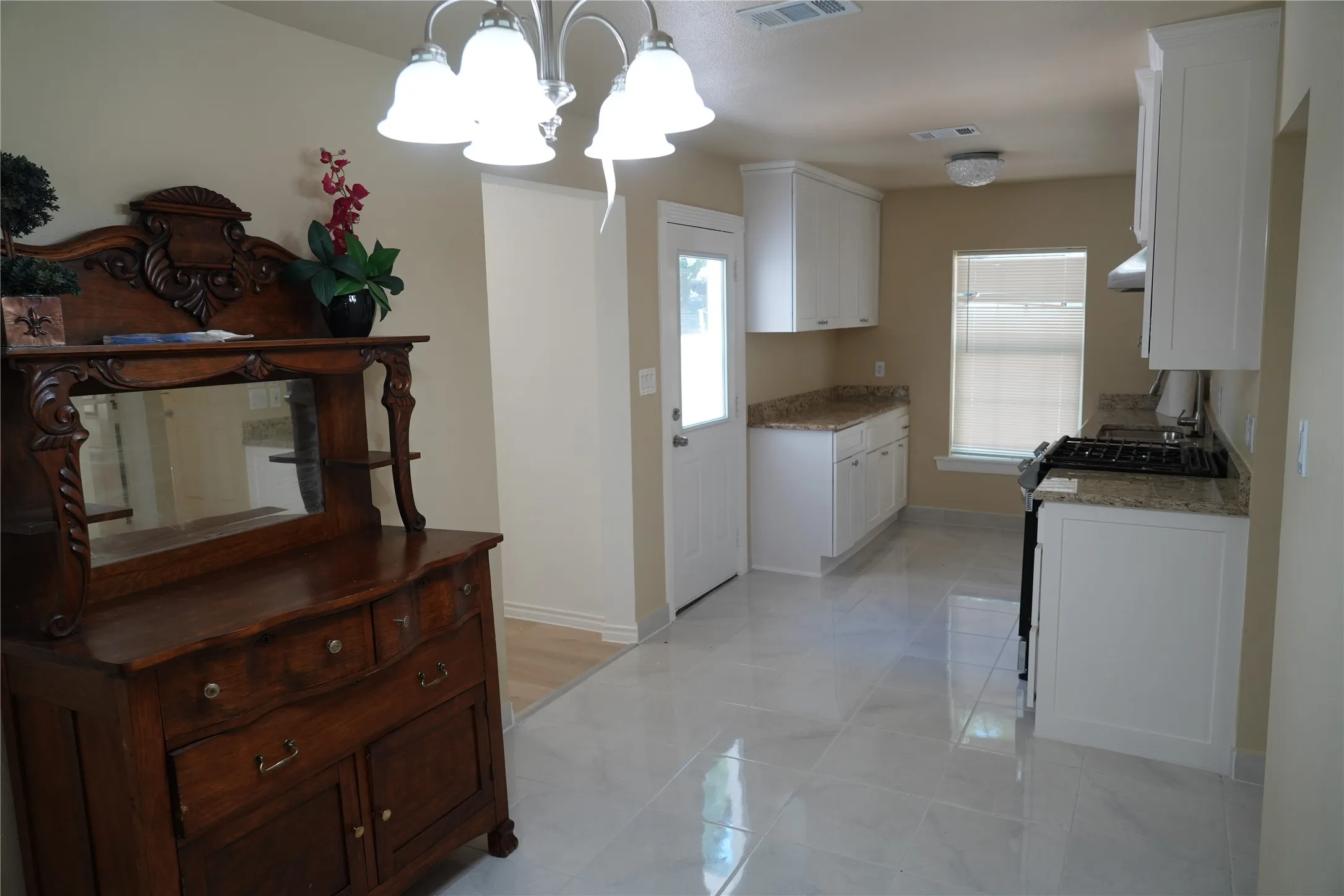 Kitchen featuring white cabinetry, light-toned countertops, tile flooring, and a stainless steel range hood