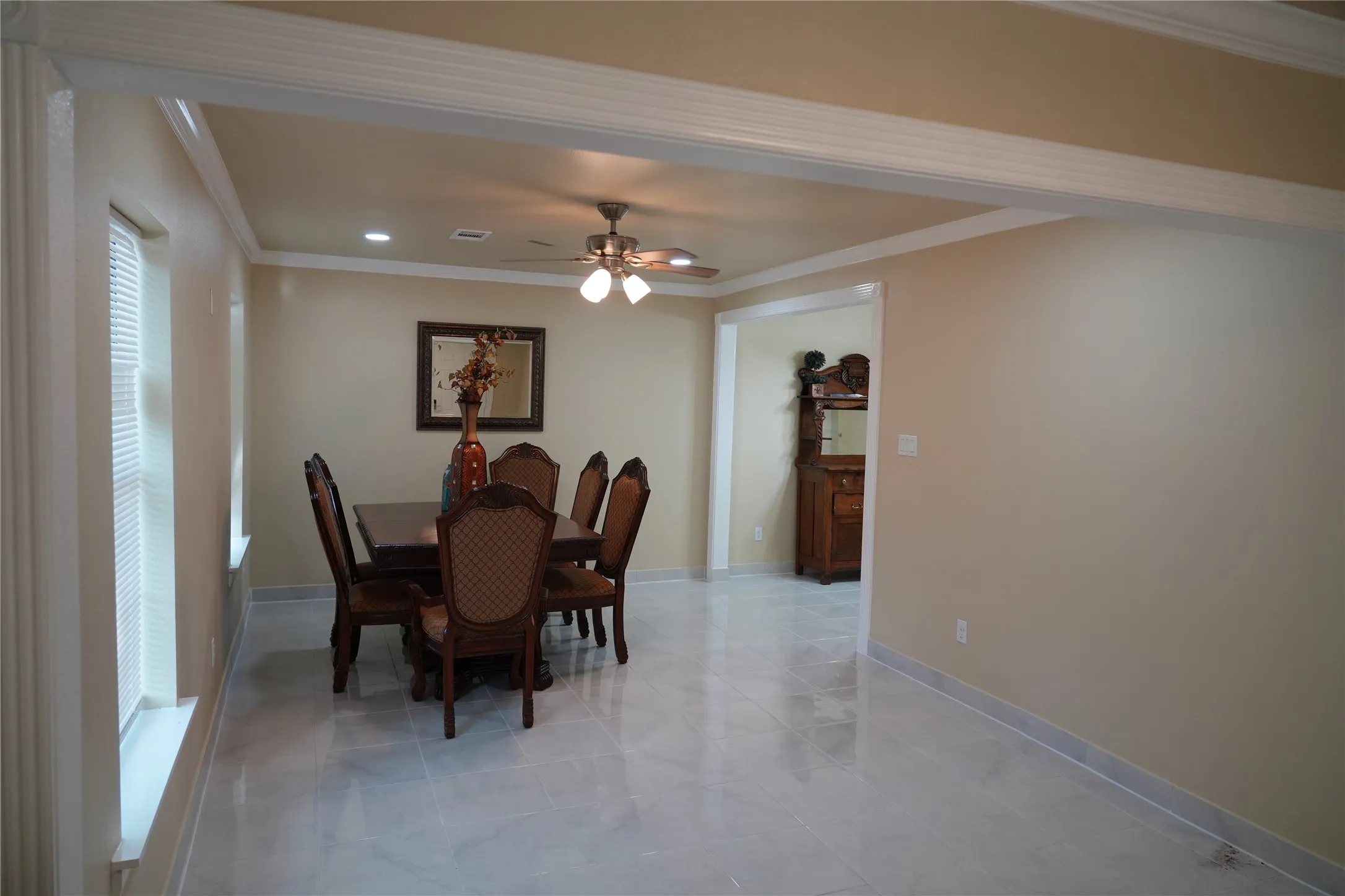 Recessed lighting, crown molding, ceiling fan, tile flooring, and a cased opening to an additional room