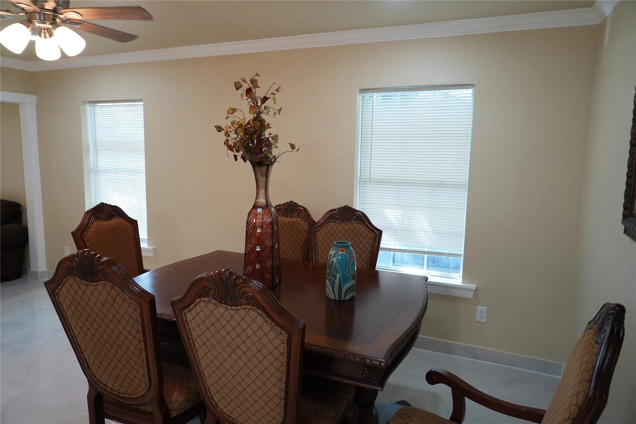 Recessed lighting, ceiling fan with light fixture, crown molding, two windows with blinds, and tile flooring