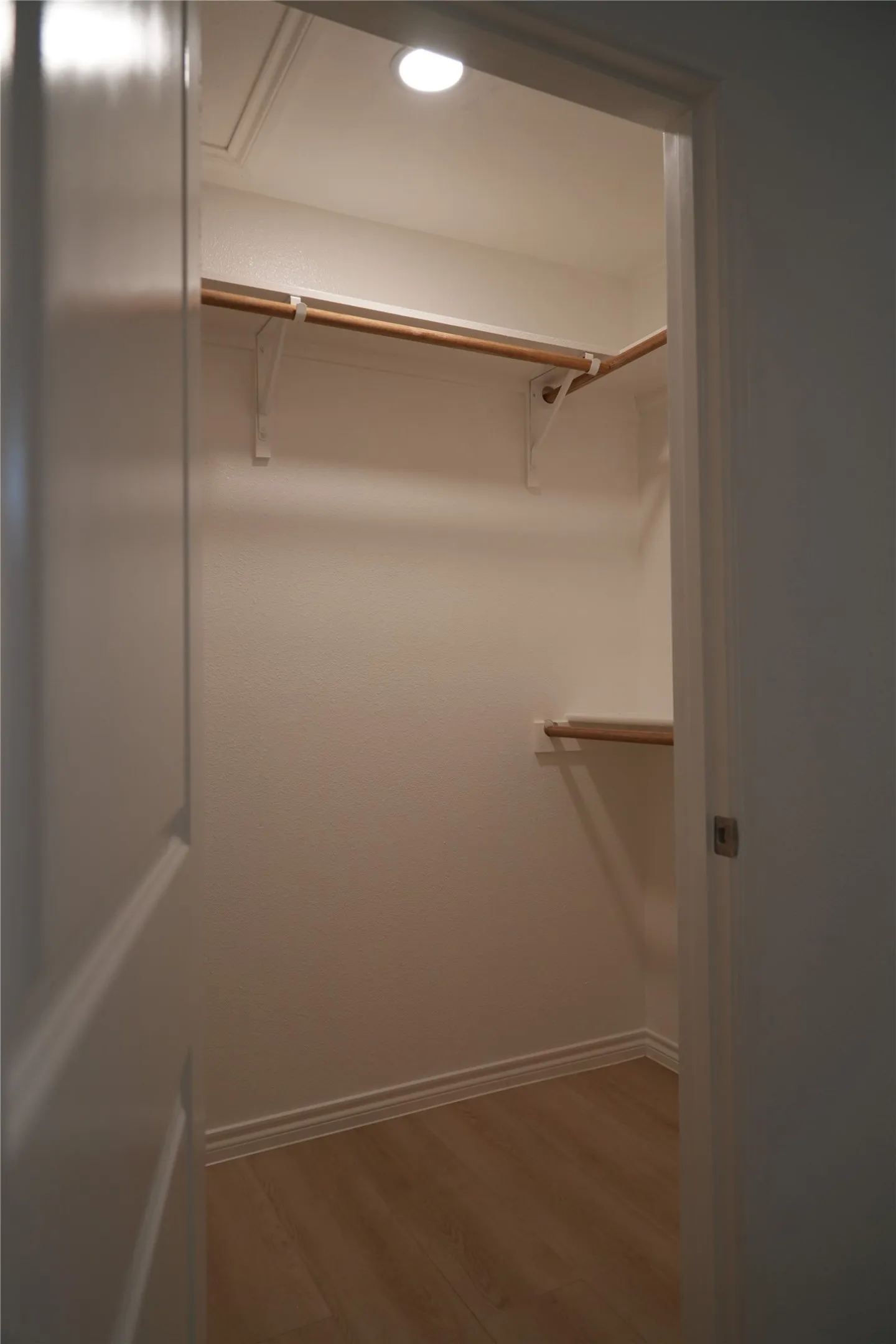 Recessed ceiling lighting, wood-finish flooring, and built-in hanging rods