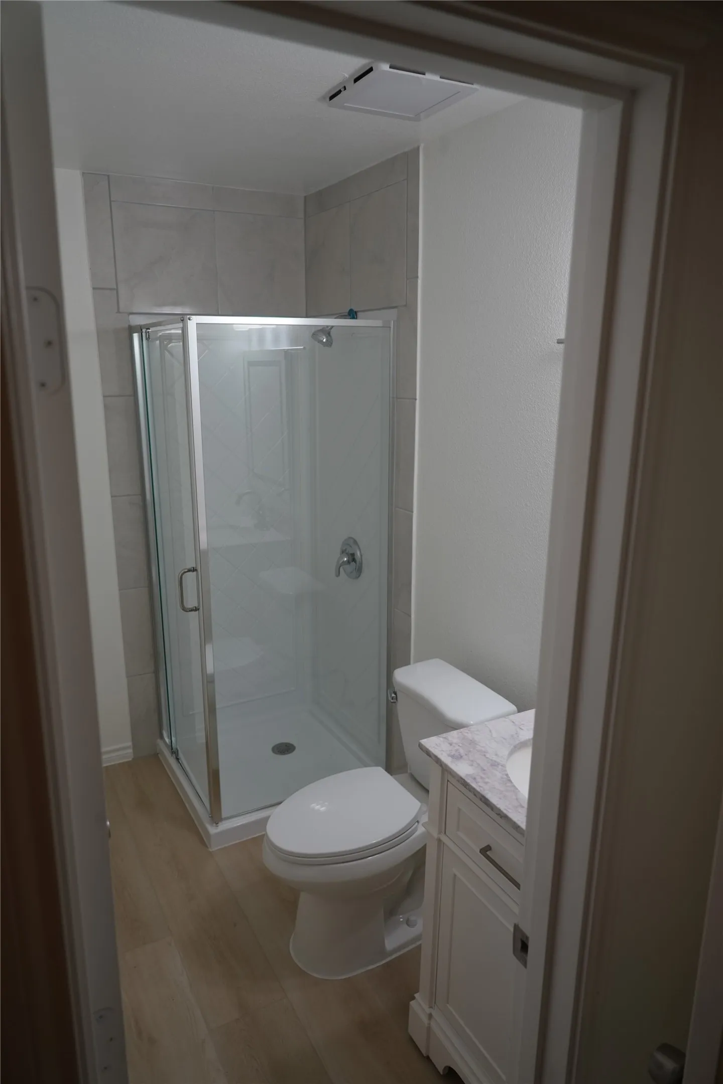 Walk-in shower with clear glass enclosure and tile surround