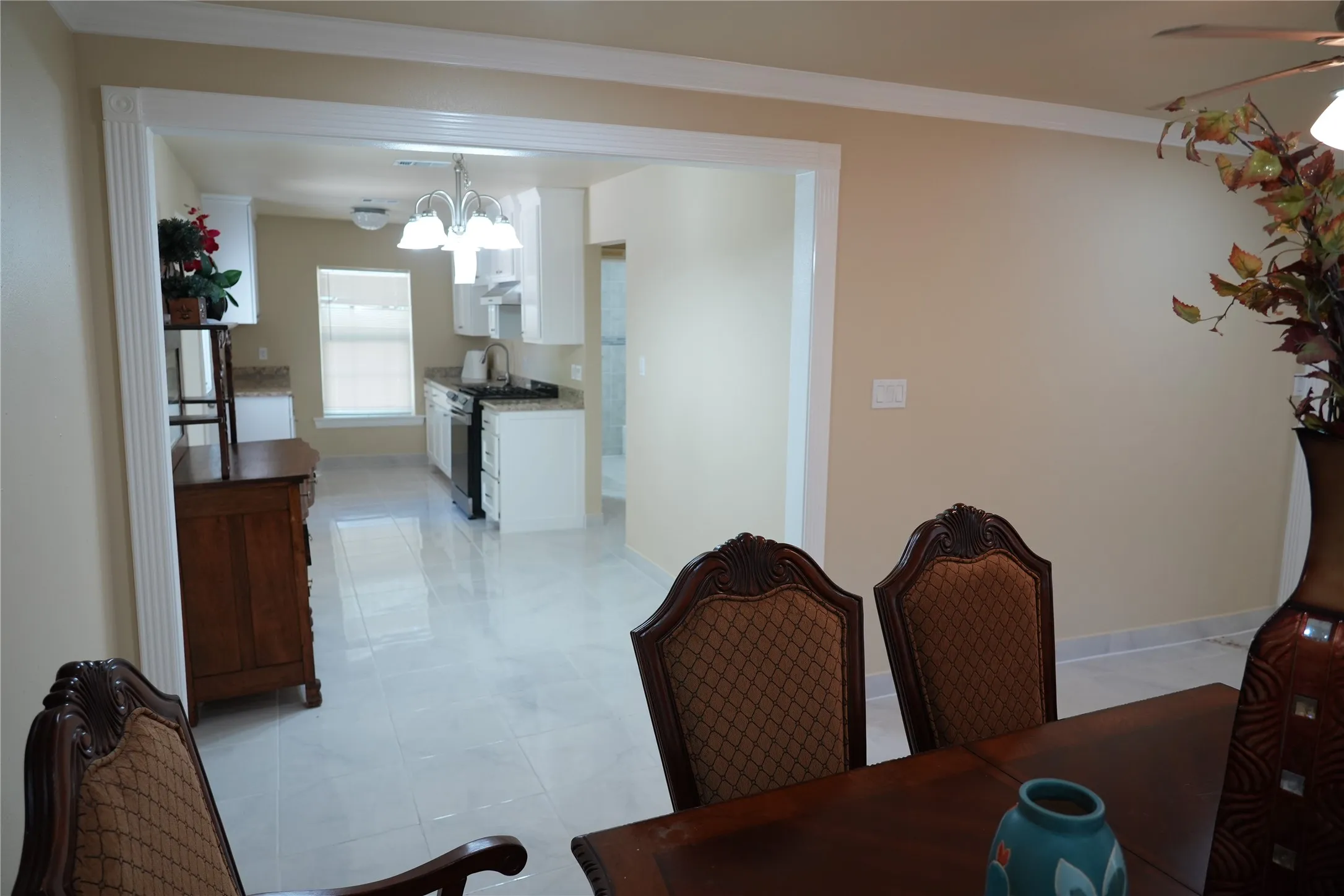 Archway entry, crown molding, tile flooring, white cabinetry, and granite countertops