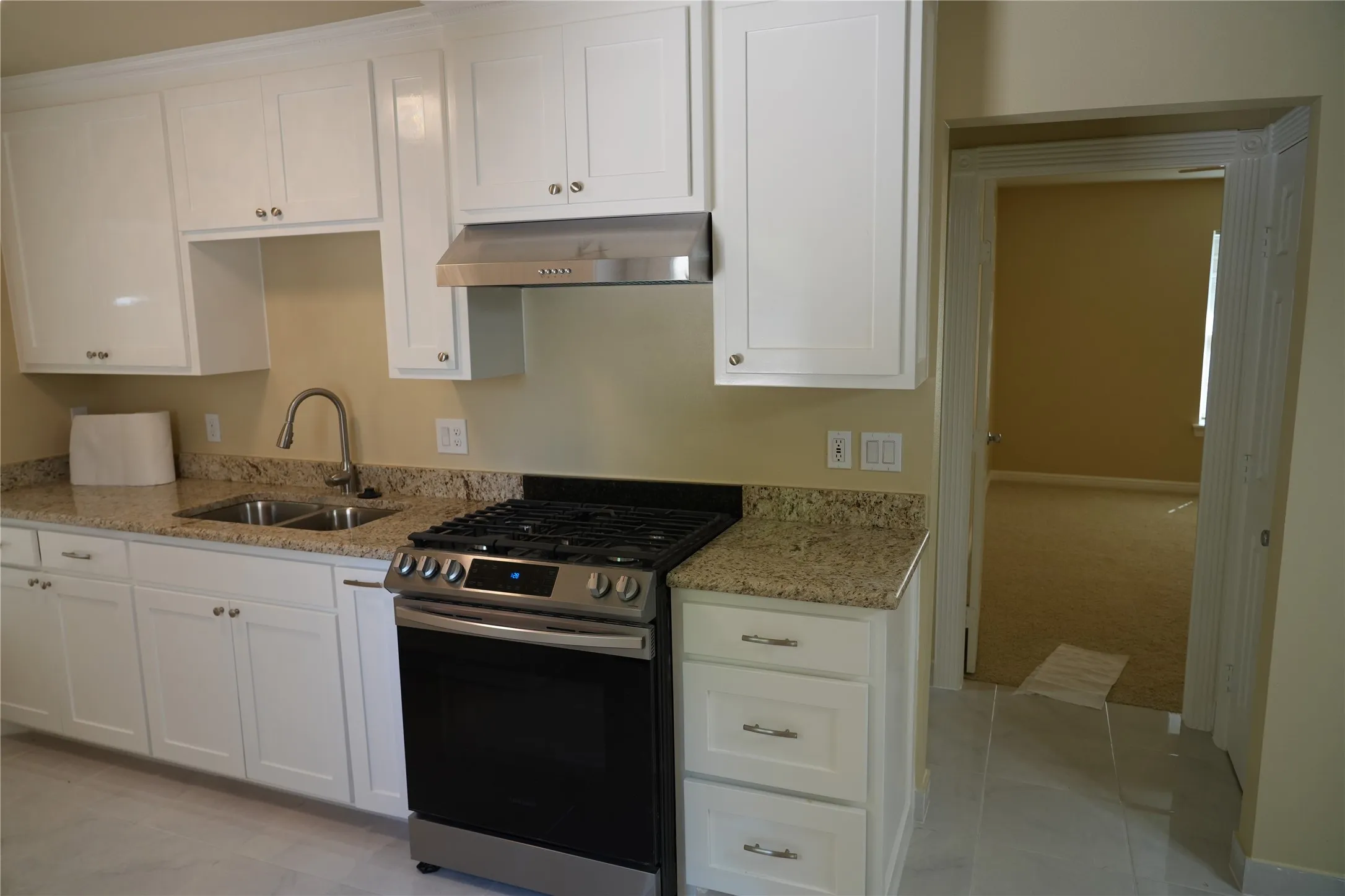 Kitchen featuring white cabinetry, light-toned speckled countertops, a stainless steel gas range, and a dual basin sink with a gooseneck faucet