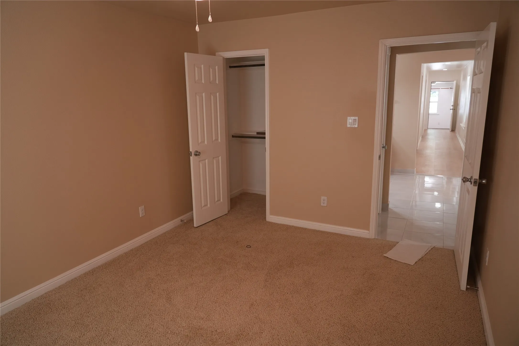 Neutral tone wall paint, textured carpeting, white panel doors, and built-in closet shelving