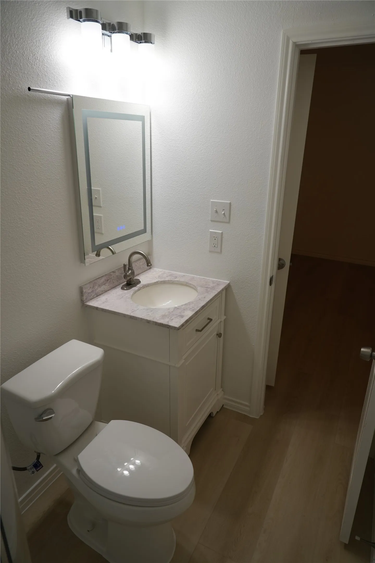 Recessed vanity with stone-finish countertop, undermount sink, and integrated mirror lighting