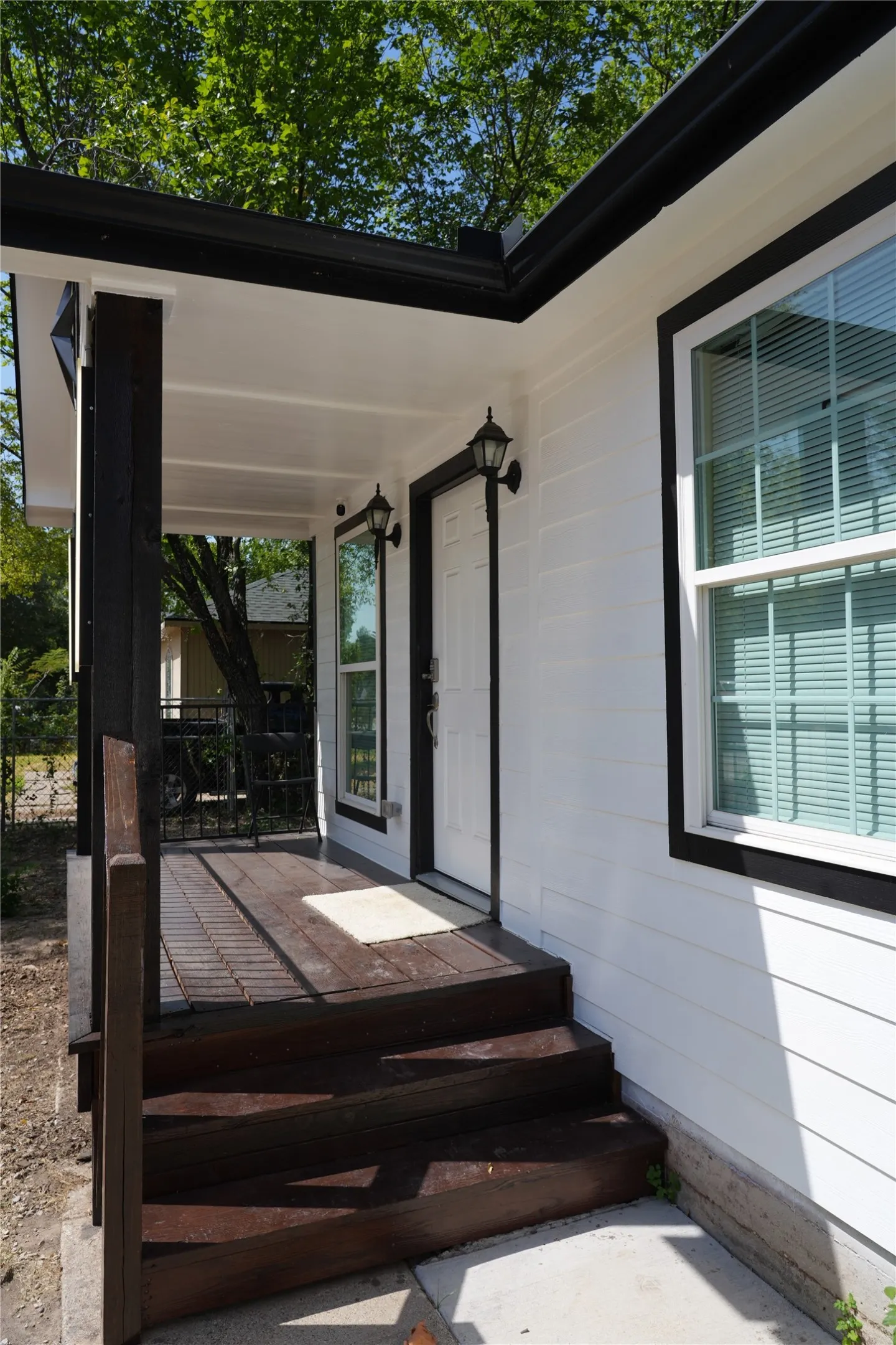 Exterior showcasing white siding, dark trim windows, and a covered porch with dark wood-finish steps