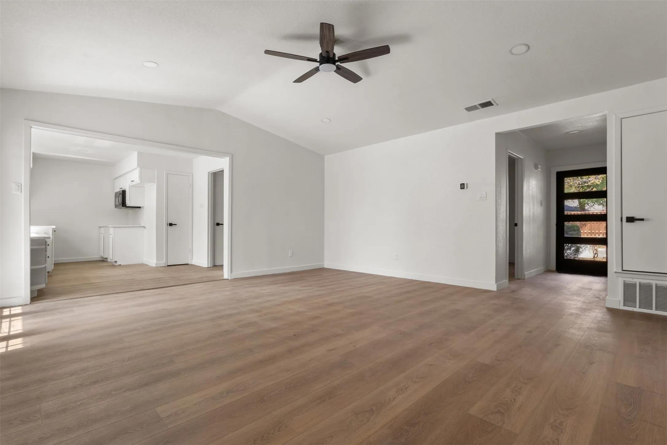 Vaulted ceiling with a ceiling fan, recessed lighting, wood-finish flooring, and a modern entry door