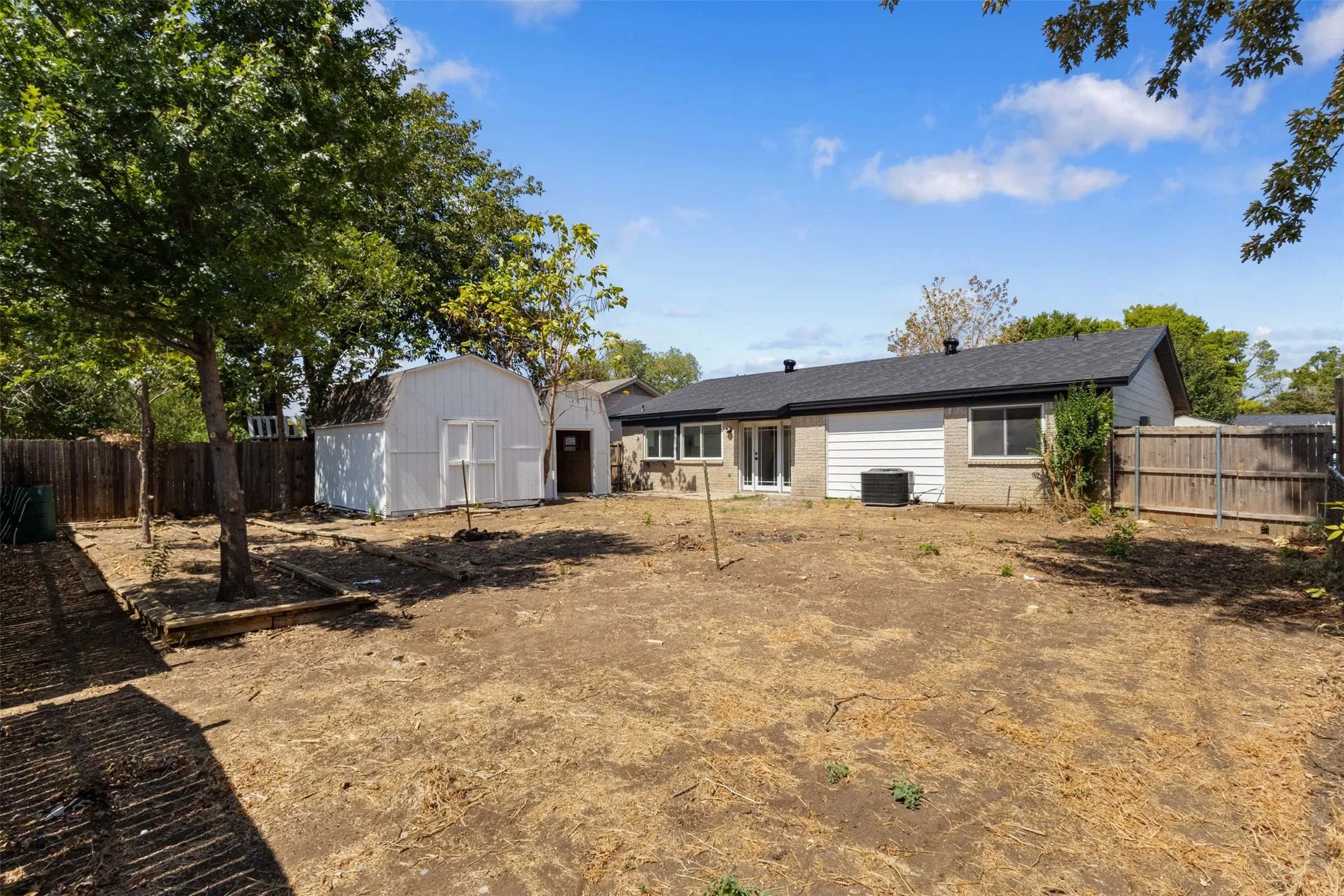 Expansive backyard with a storage shed, wood fencing, and mature trees