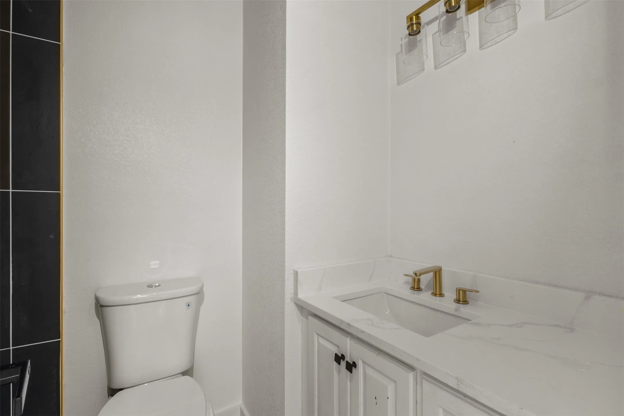 White vanity with gold-finish hardware, rectangular undermount sink, and white countertop