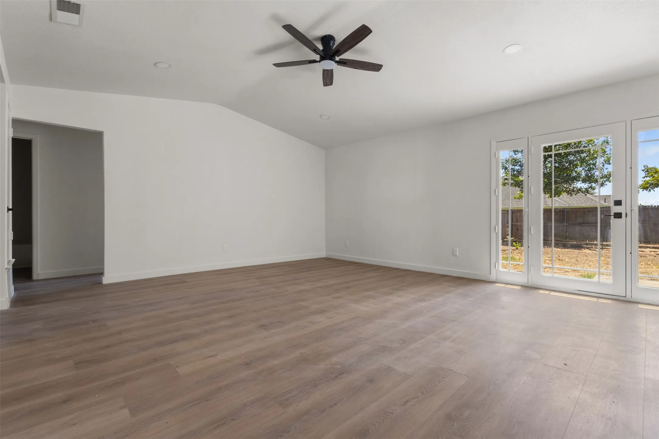 Vaulted ceiling with a ceiling fan, wood-finish flooring, recessed lighting, and French doors