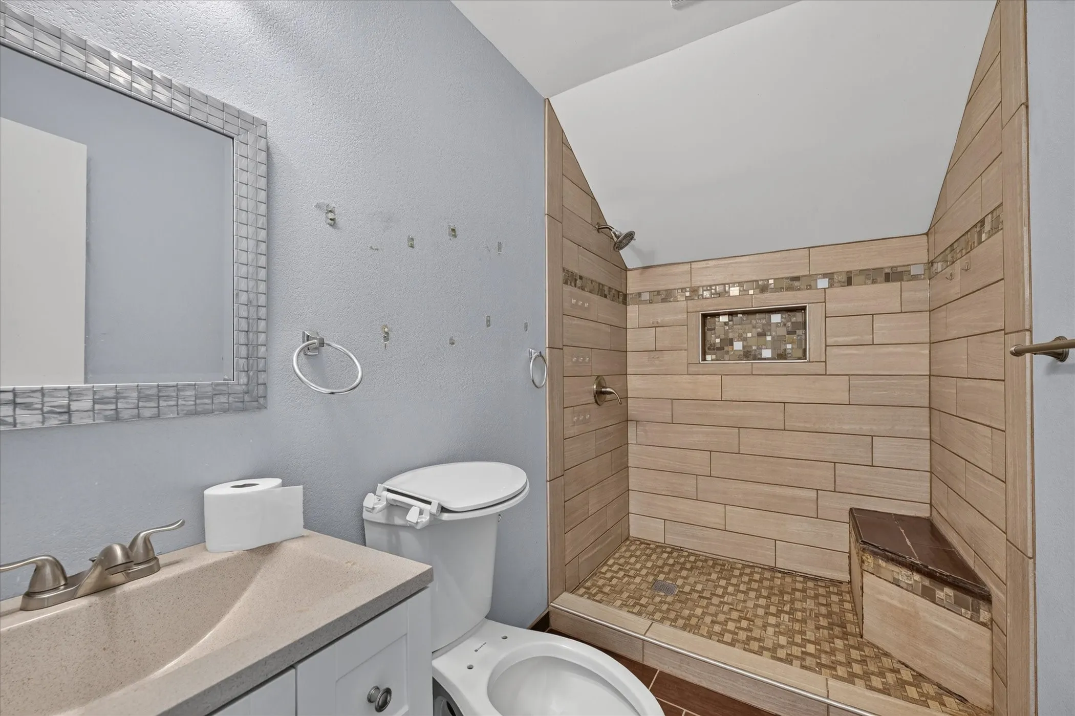 Walk-in shower with horizontal tile, mosaic tile accent, and built-in bench