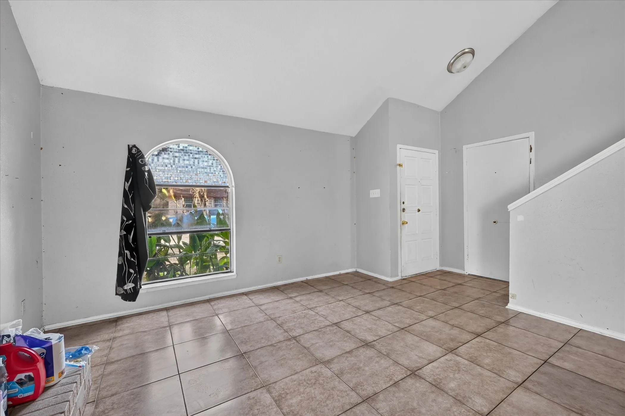 Tile flooring, vaulted ceiling, arched window, and a built-in stairwell