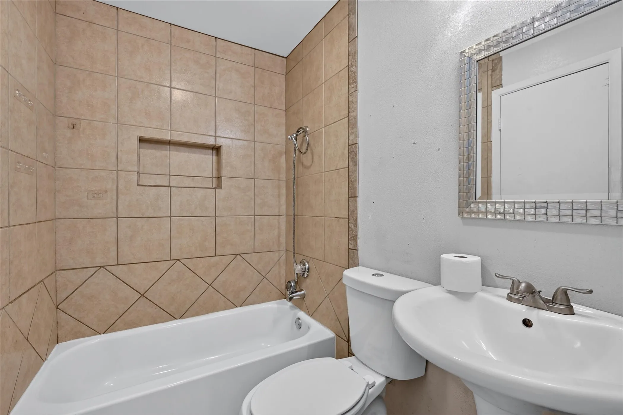 Full bath with pedestal sink, toilet, and a tiled tub shower combination