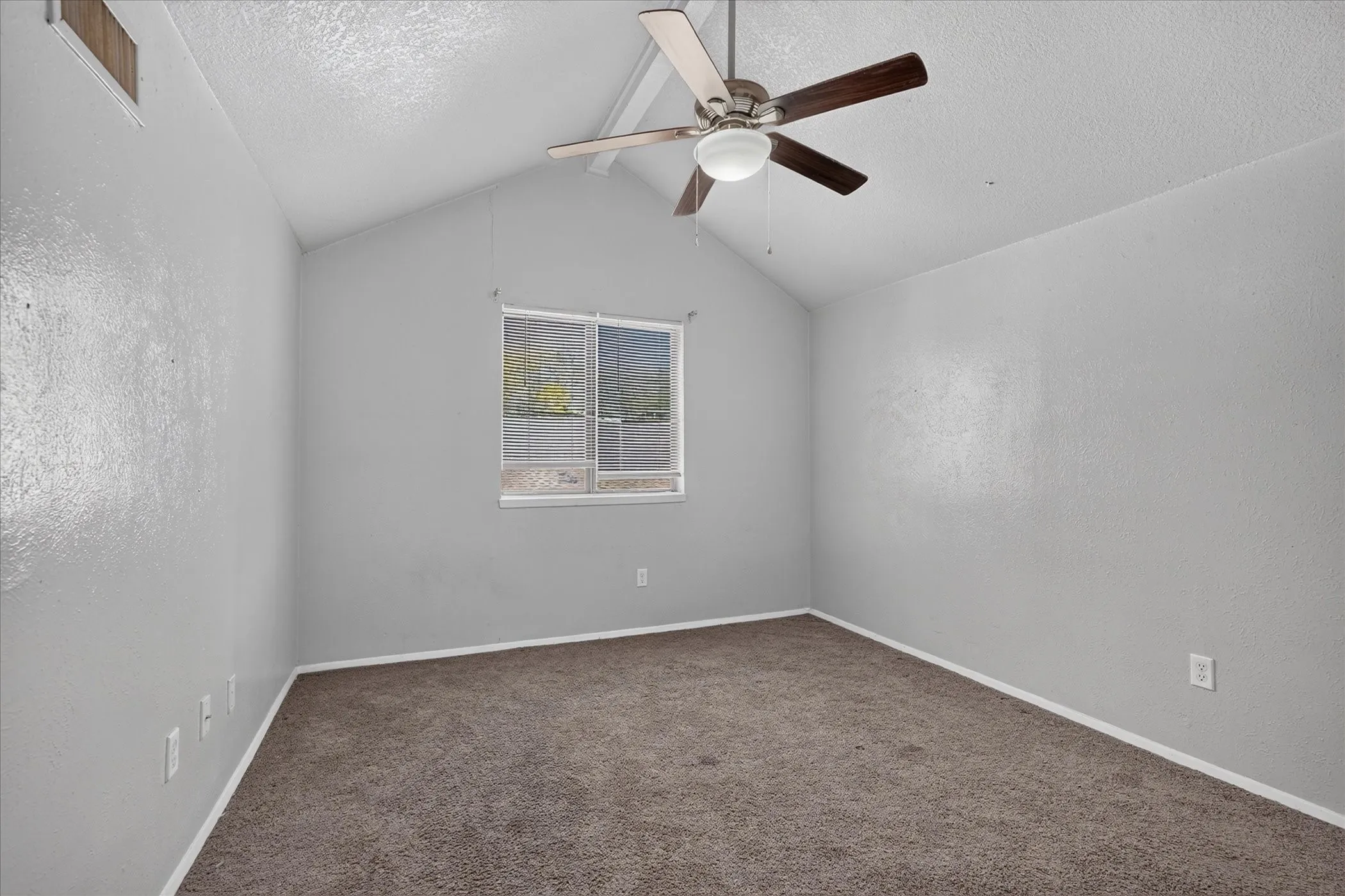 Vaulted ceilings with a ceiling fan light fixture, window with blinds, and neutral carpeting