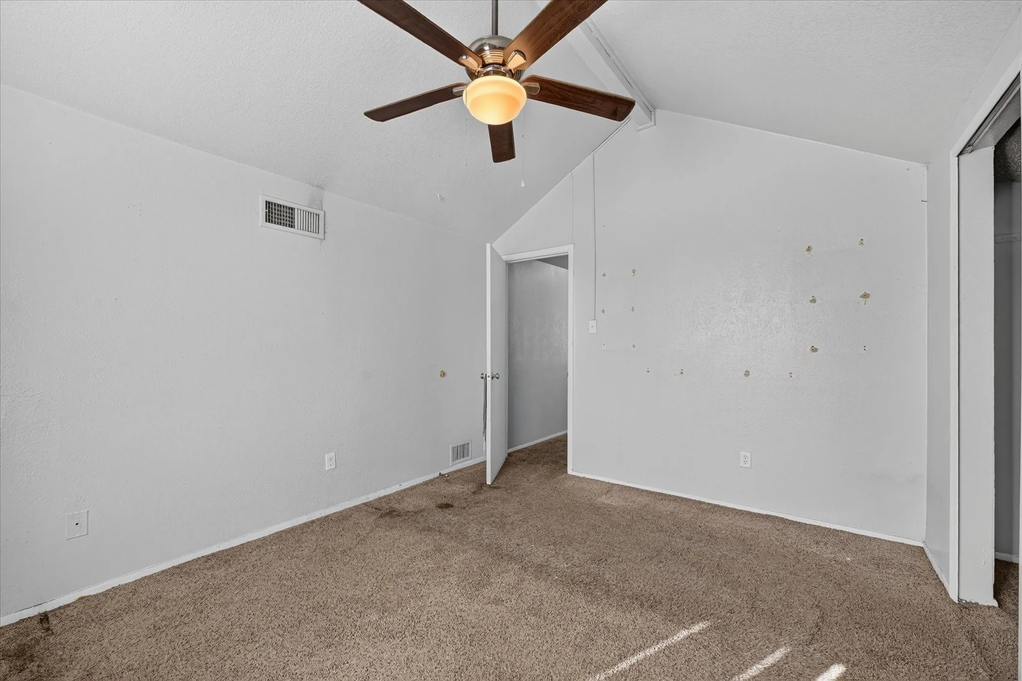Vaulted ceiling with a ceiling fan, light-colored walls, and carpet flooring