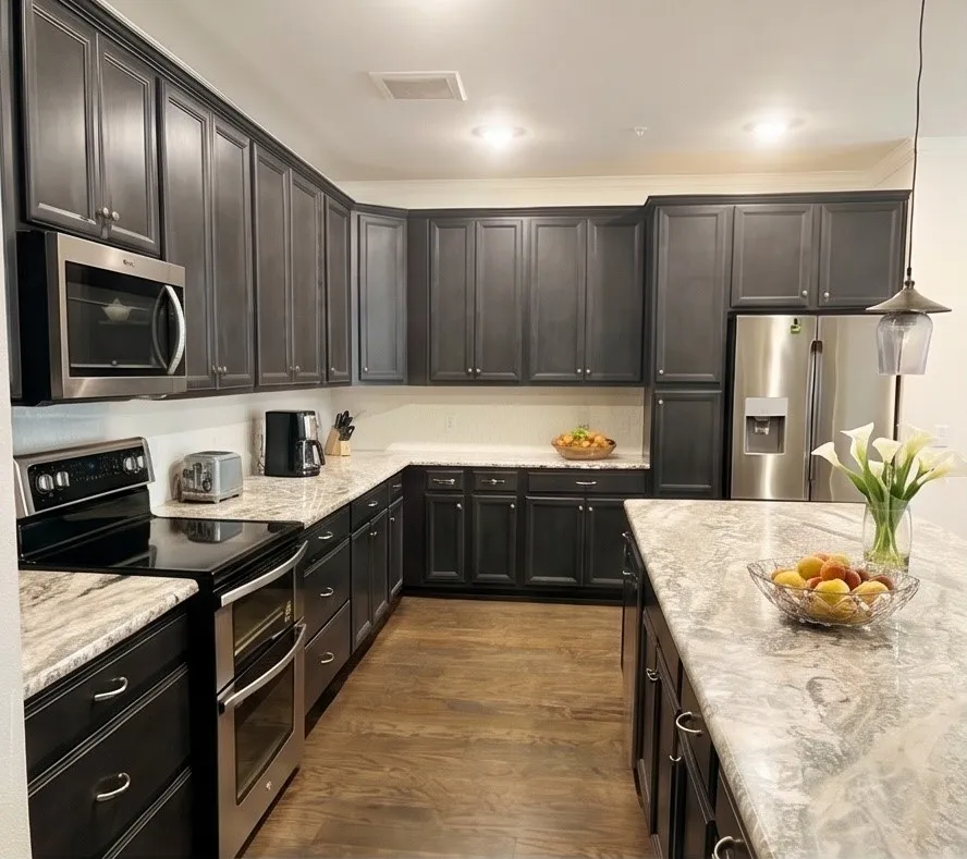 Kitchen featuring dark wood-finish cabinetry, light-toned countertops, stainless steel appliances, a kitchen island, and wood-finish flooring