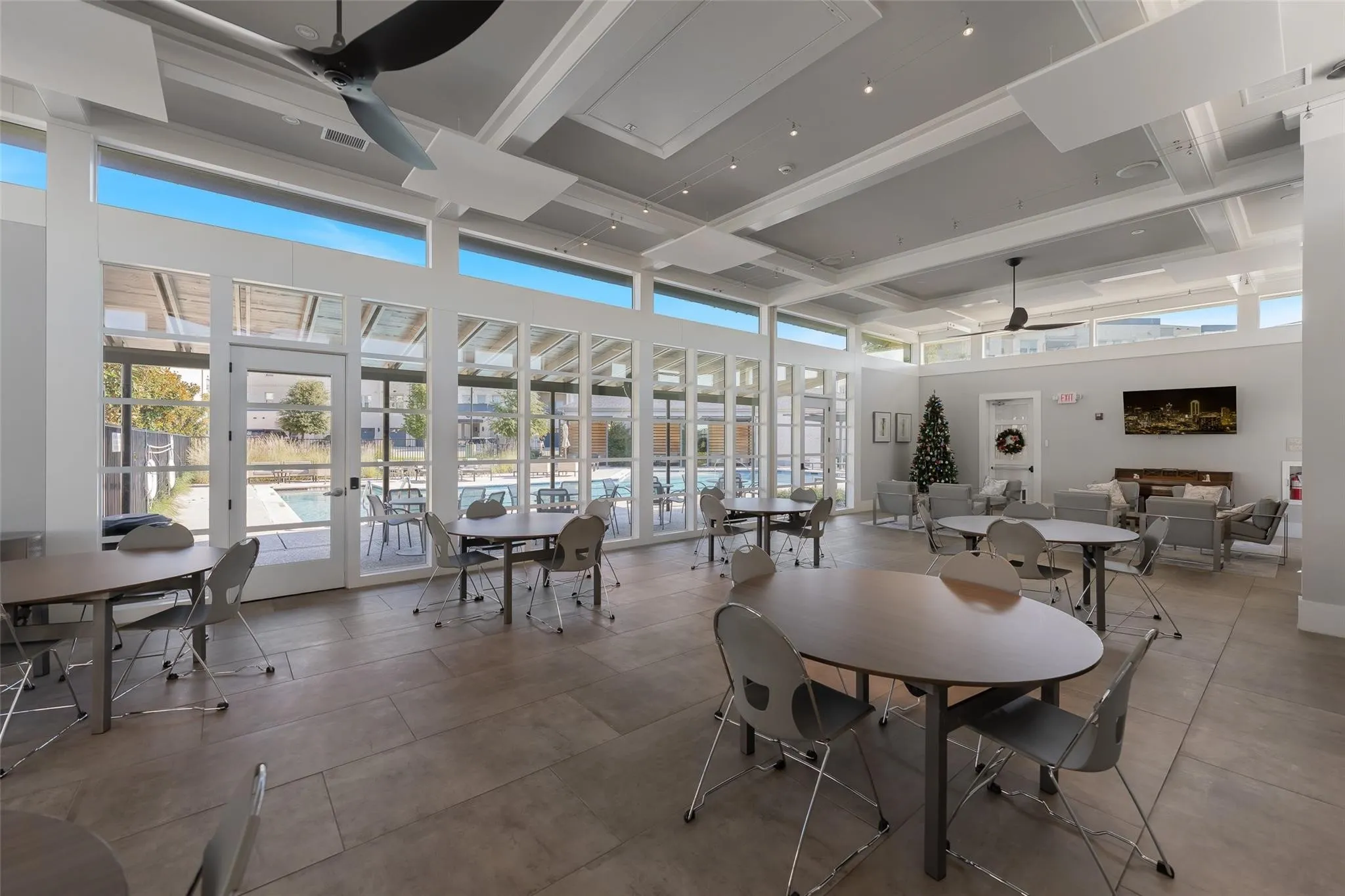 Spacious community room with a coffered ceiling, large ceiling fans, and expansive windows