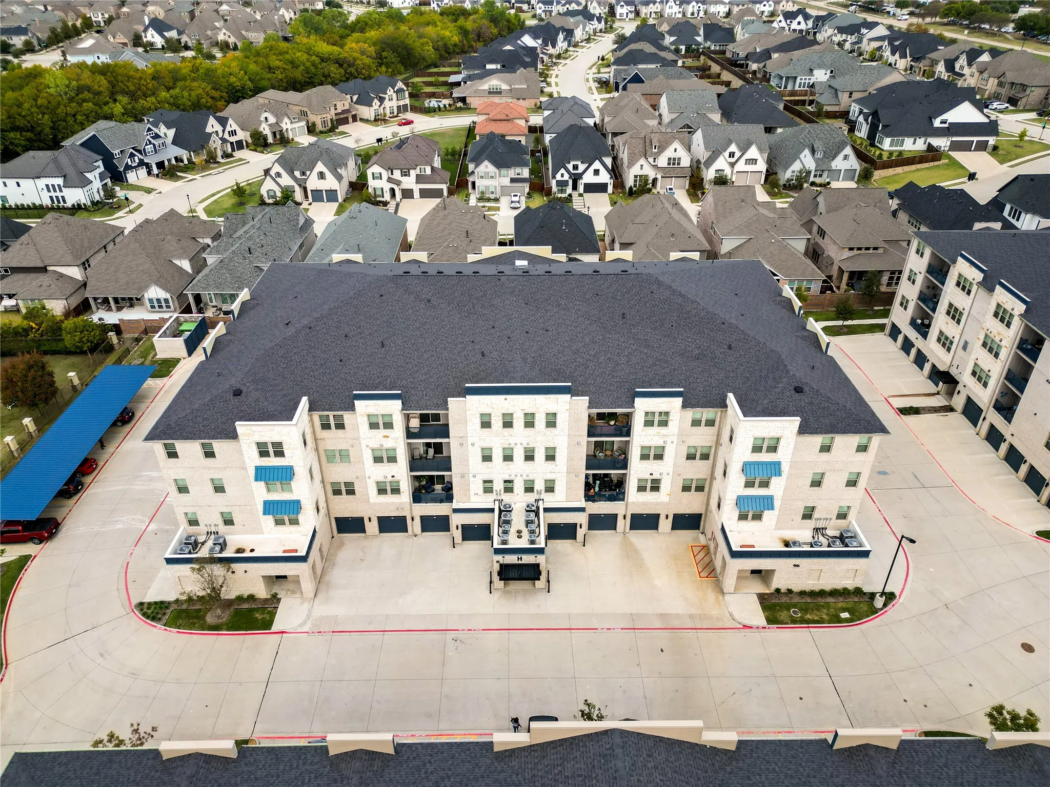 Multi-story building featuring balconies, blue awnings, and an attached covered parking structure