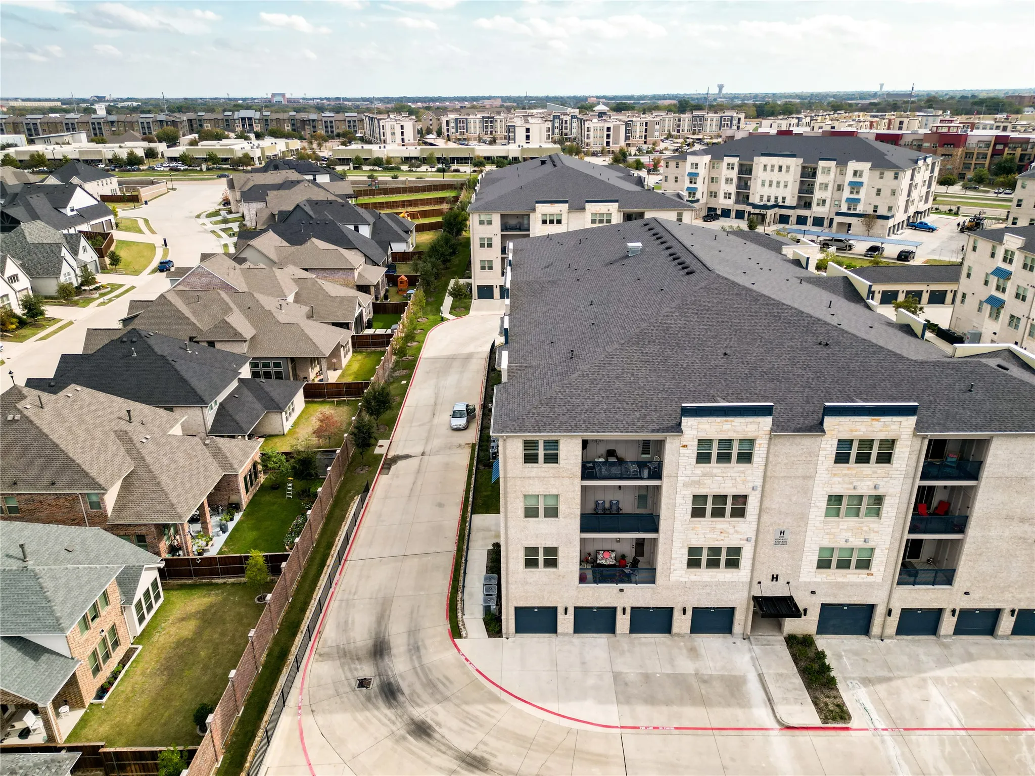 Contemporary apartment building with stone and siding exterior, private balconies, and integrated garage spaces