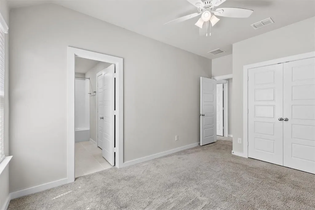 Vaulted ceiling with a ceiling fan, carpeted flooring, and white paneled doors