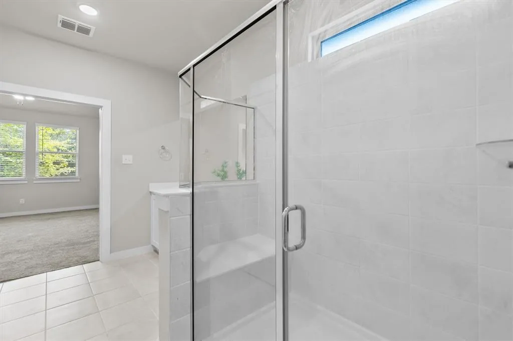 Glass-enclosed shower with a built-in bench, white tile walls, and a transom window