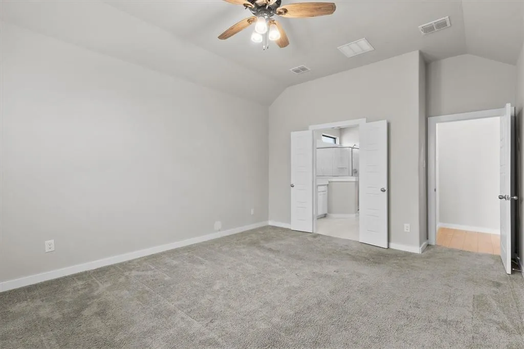 Vaulted ceiling with a ceiling fan, plush carpet flooring, light-toned wall paint, and white paneled doors