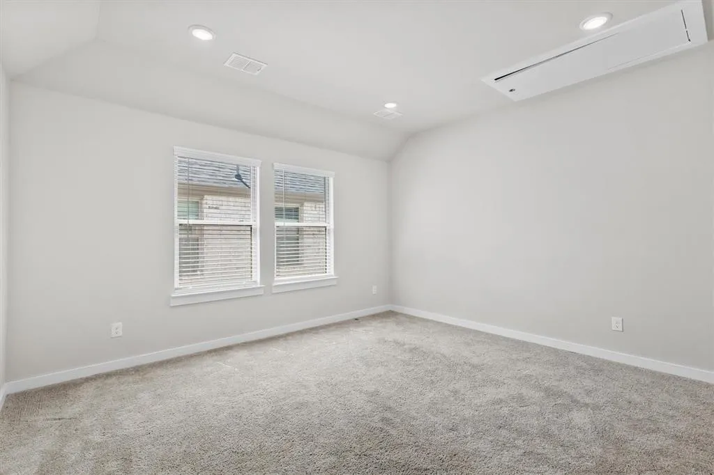 Recessed lighting, double windows with blinds, gray carpeting, and a ceiling-mounted air conditioning unit