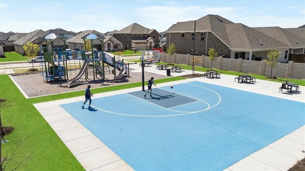 Community amenity area featuring a basketball court, playground equipment, and picnic tables