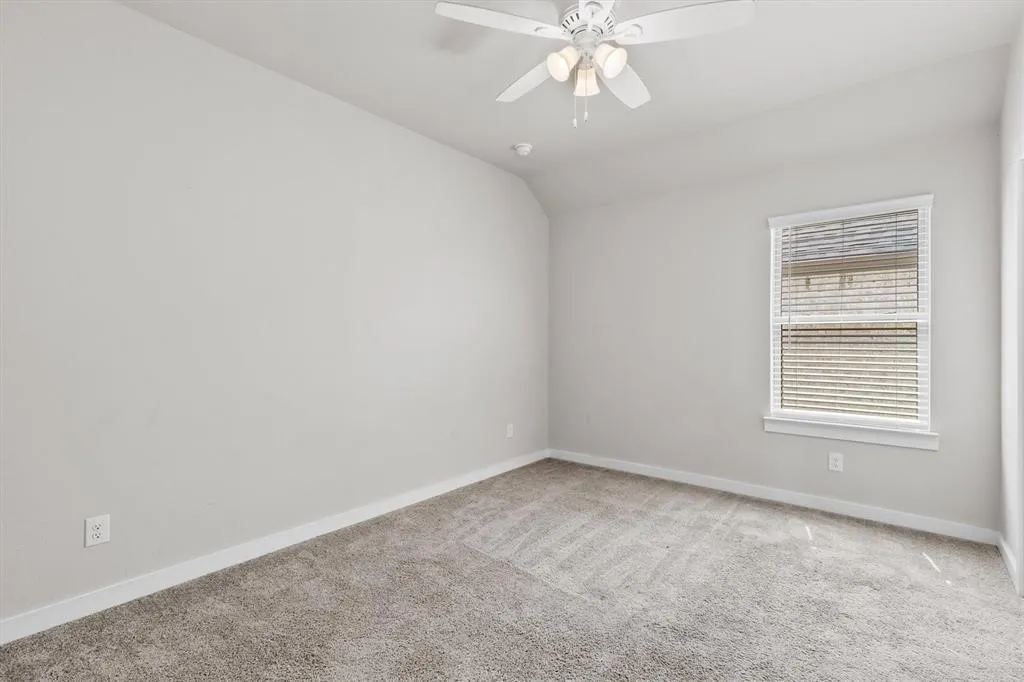 Neutral wall paint, ceiling fan with integrated lighting, window with blinds, and carpeting