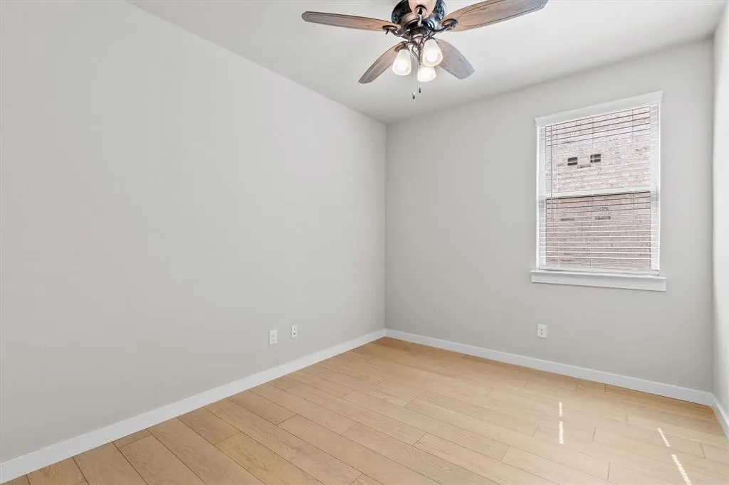 Recessed window with horizontal blinds, wood-finish flooring, ceiling fan with light fixture, and neutral wall tones