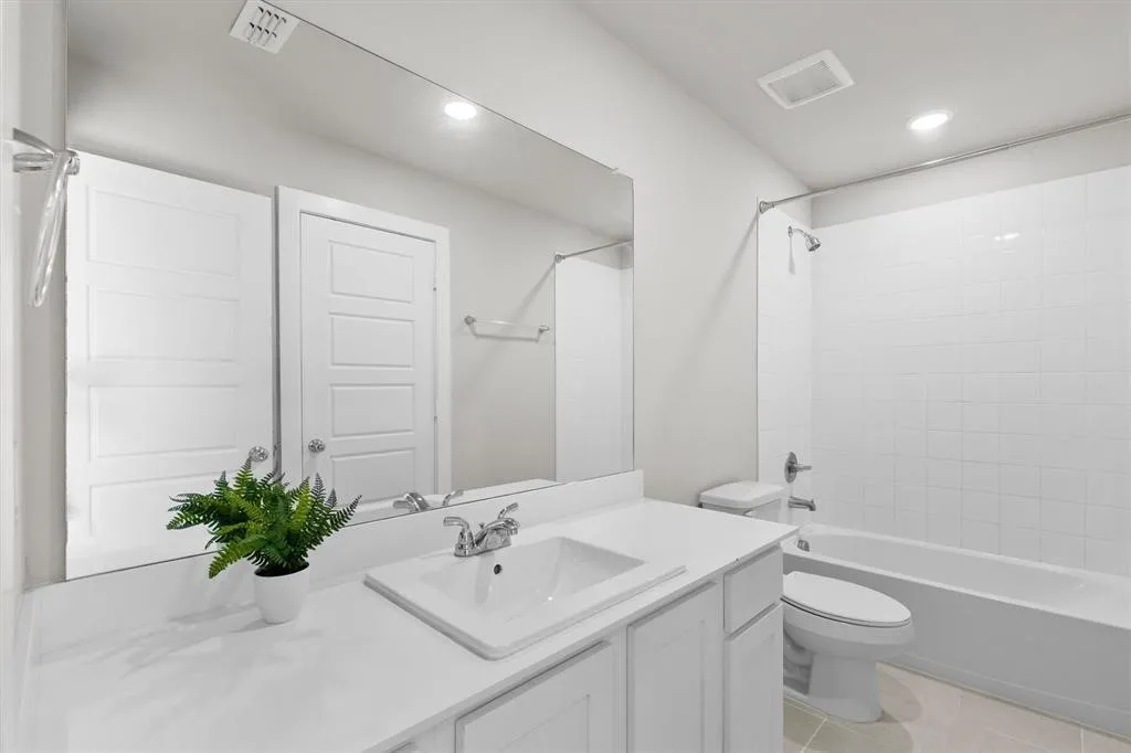 Spa-inspired bathroom featuring a frameless glass shower enclosure, white subway tile surround, and dual vanity with white cabinetry and white quartz countertop