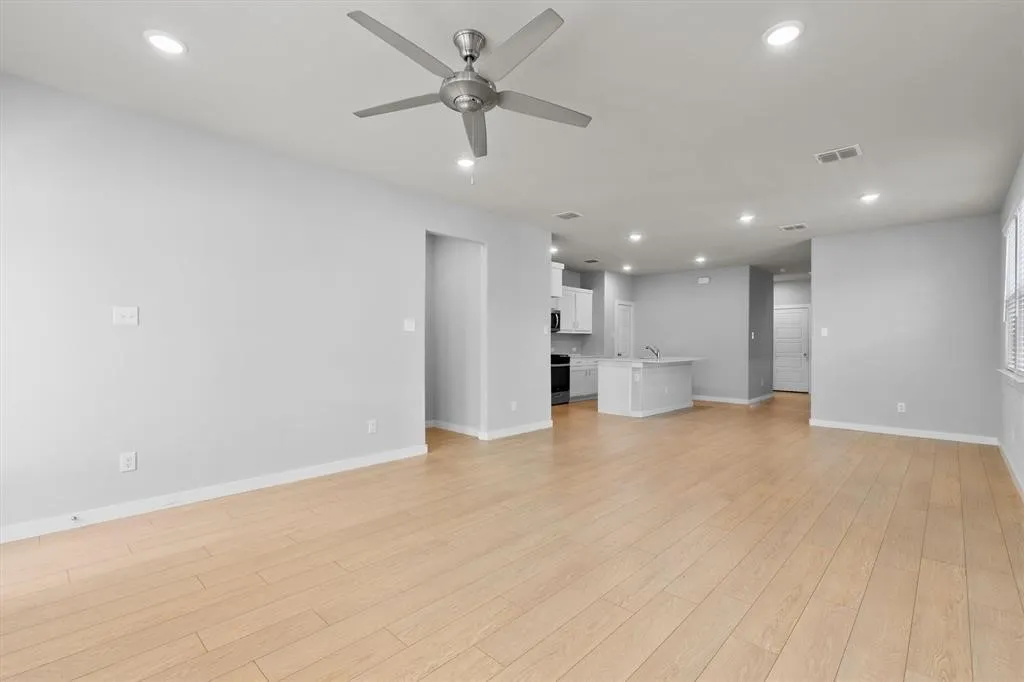 Open-concept living space featuring wood-finish flooring, recessed lighting, and a ceiling fan