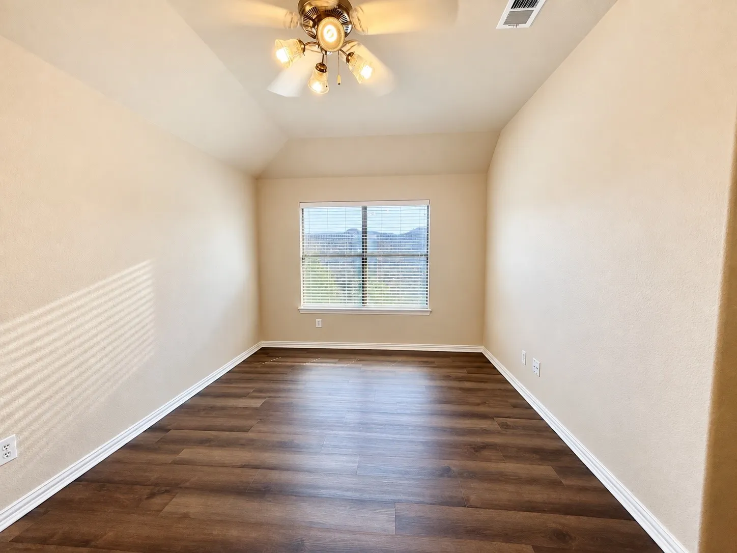 Vaulted ceiling with a ceiling fan, window with horizontal blinds, wood-finish flooring, and light-toned walls