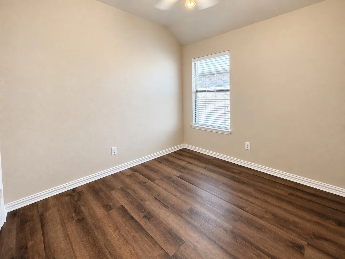 Wood-finish flooring, neutral wall tones, white trim, and a ceiling fan with integrated lighting