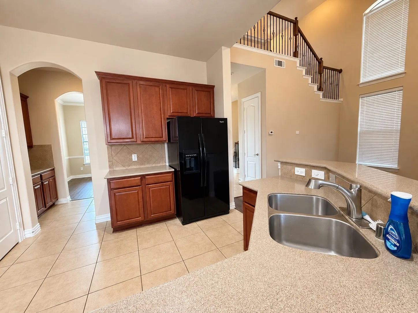 Kitchen featuring a stainless steel double basin sink, expansive countertops, tile flooring, and wood​​‌​​​​‌​​‌‌​‌‌​​​‌‌​‌​‌​‌​​​‌​​ cabinetry