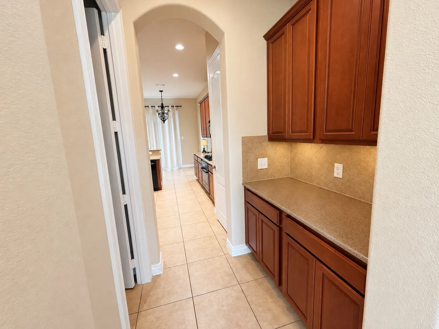 Built-in cabinetry with wood-finish doors, solid surface countertop, tile backsplash, and recessed lighting