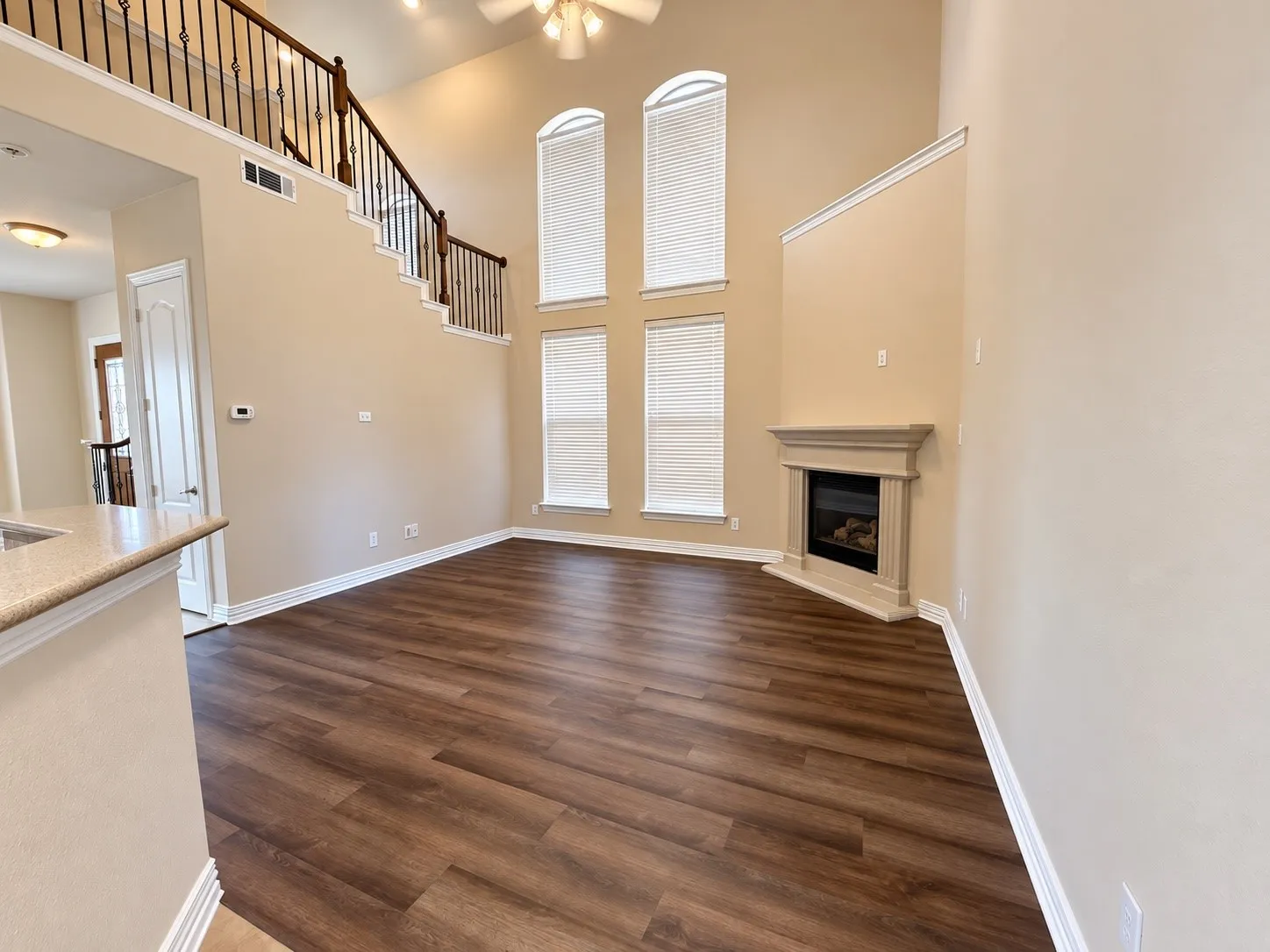 Living area featuring high ceilings, wood-finish flooring, a built-in fireplace, and a second-story interior balcony with an ornate railing