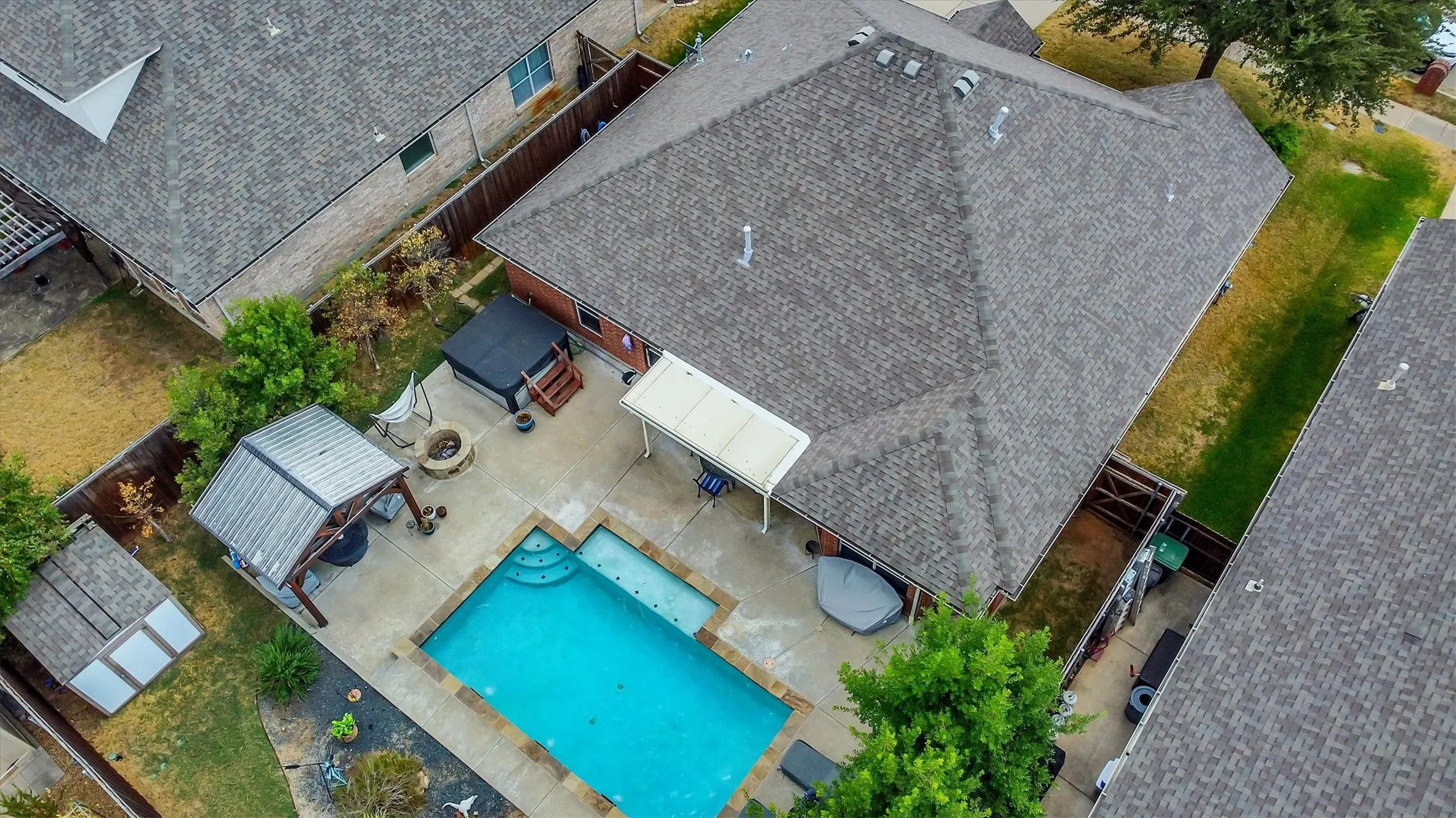 Private backyard with a rectangular swimming pool, a covered patio, a separate hot tub, a fire pit, and a detached shed