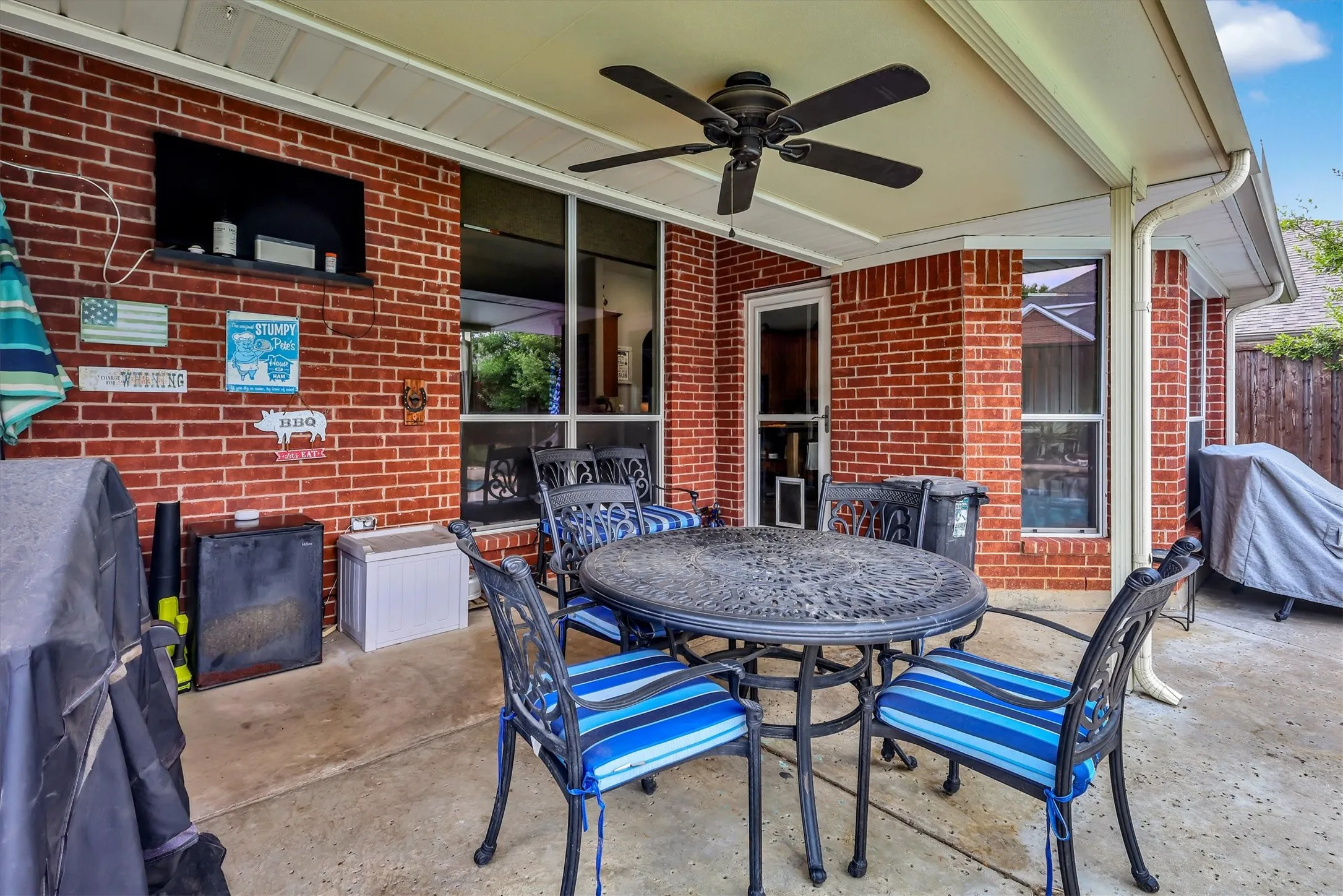 Covered patio featuring a ceiling fan, brick exterior, and concrete flooring