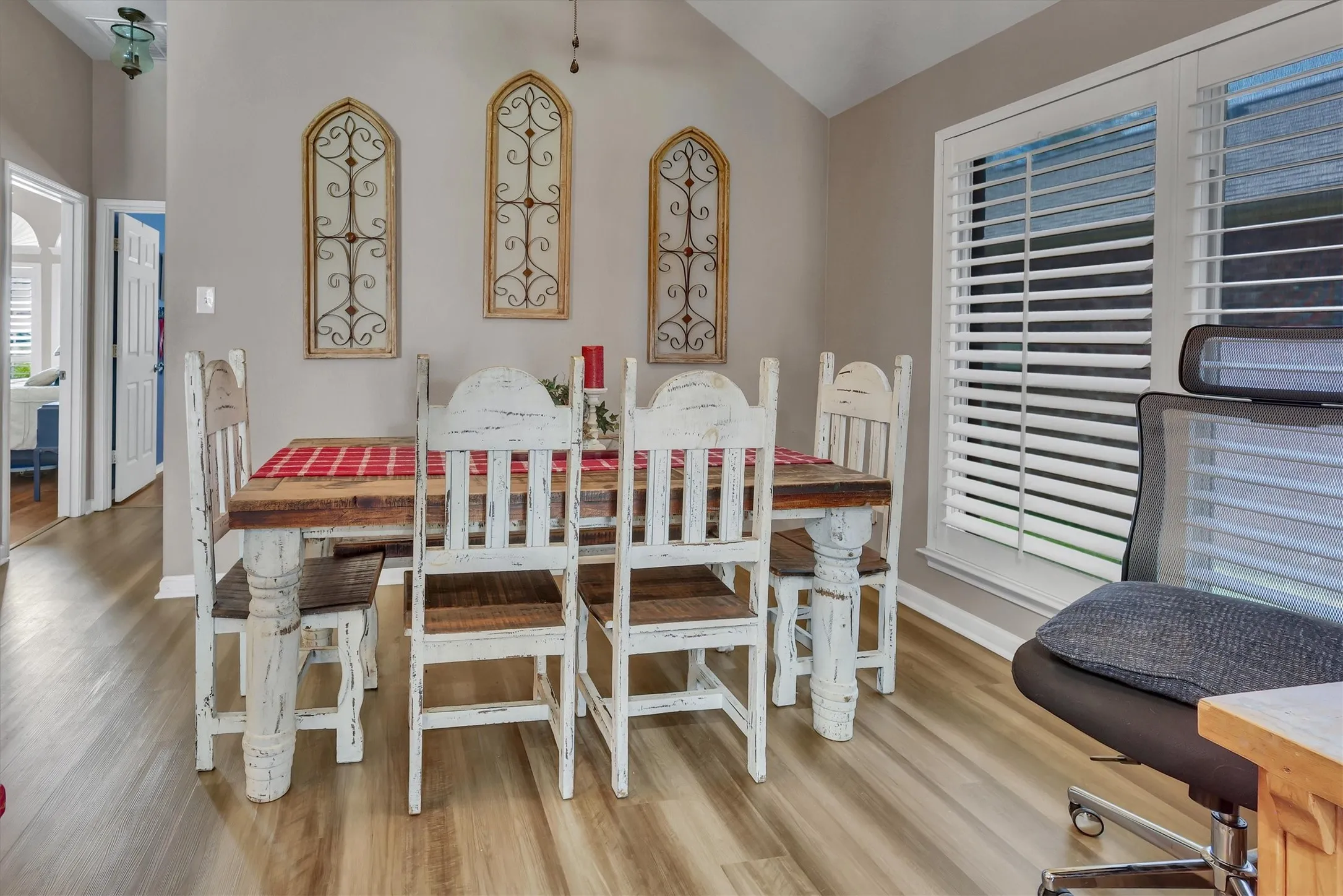 Vaulted ceiling, wood-finish flooring, and white window shutters